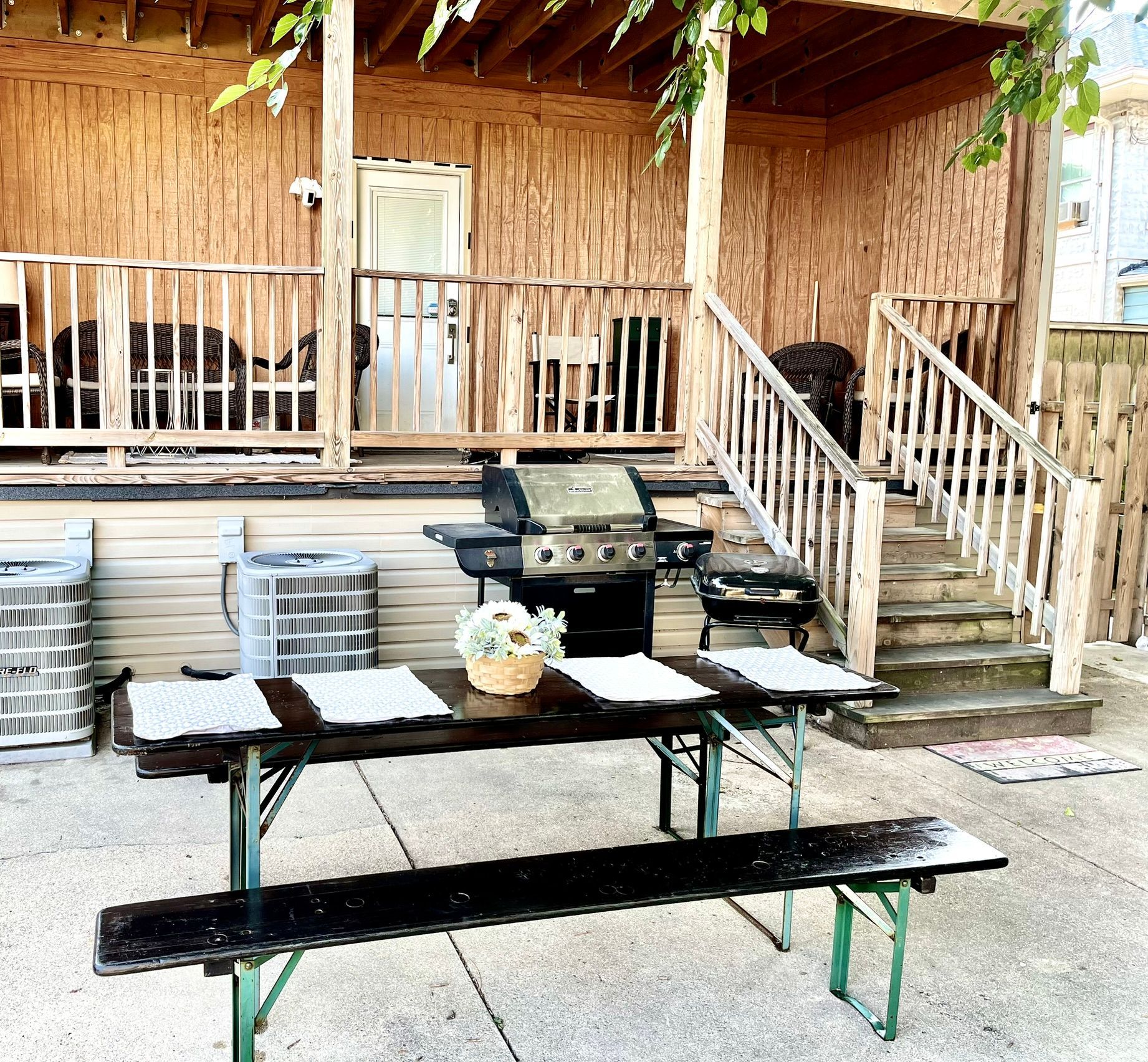 A porch with a table and benches and a grill.