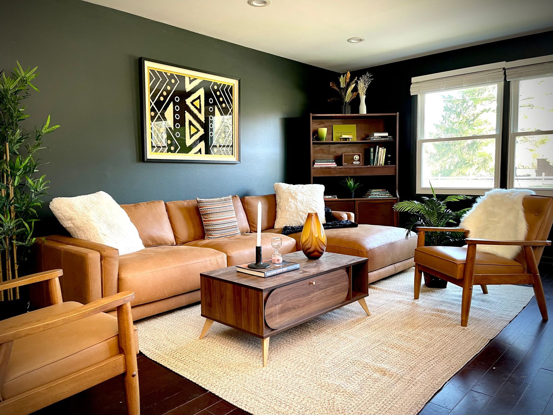 A living room with a couch , chairs , a coffee table and a picture on the wall.