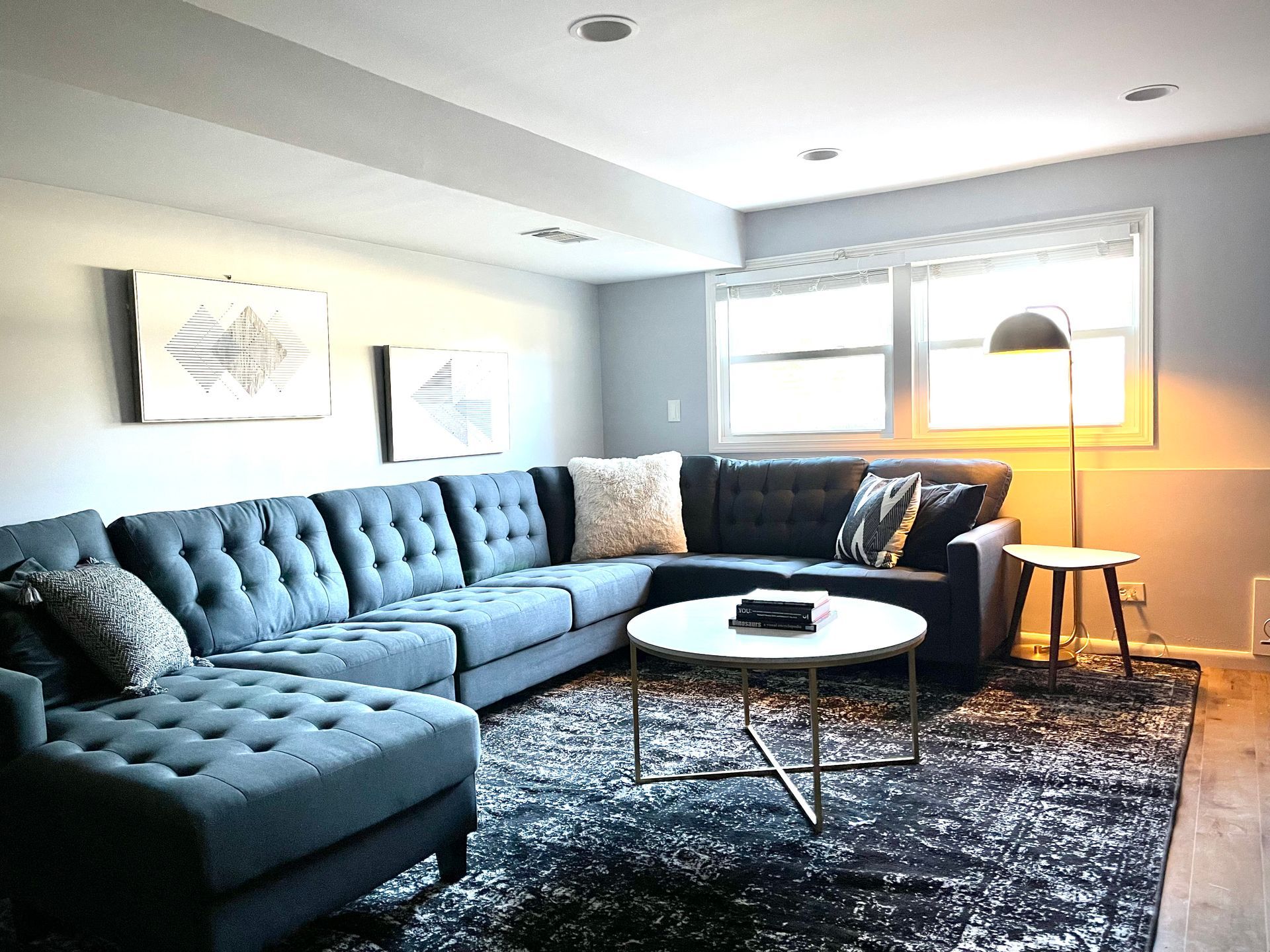 A living room with a large sectional couch and a round coffee table.