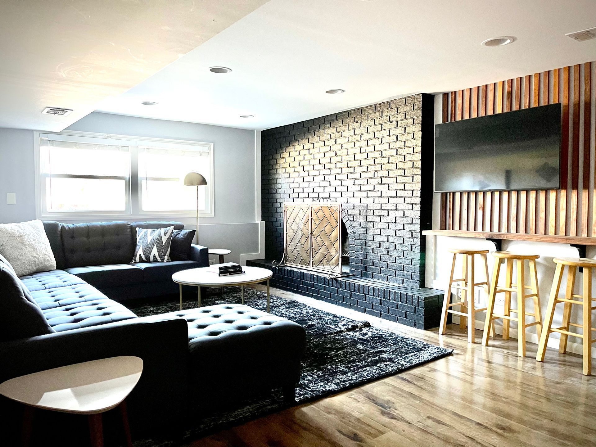 A living room with a couch , chairs , stools and a fireplace.