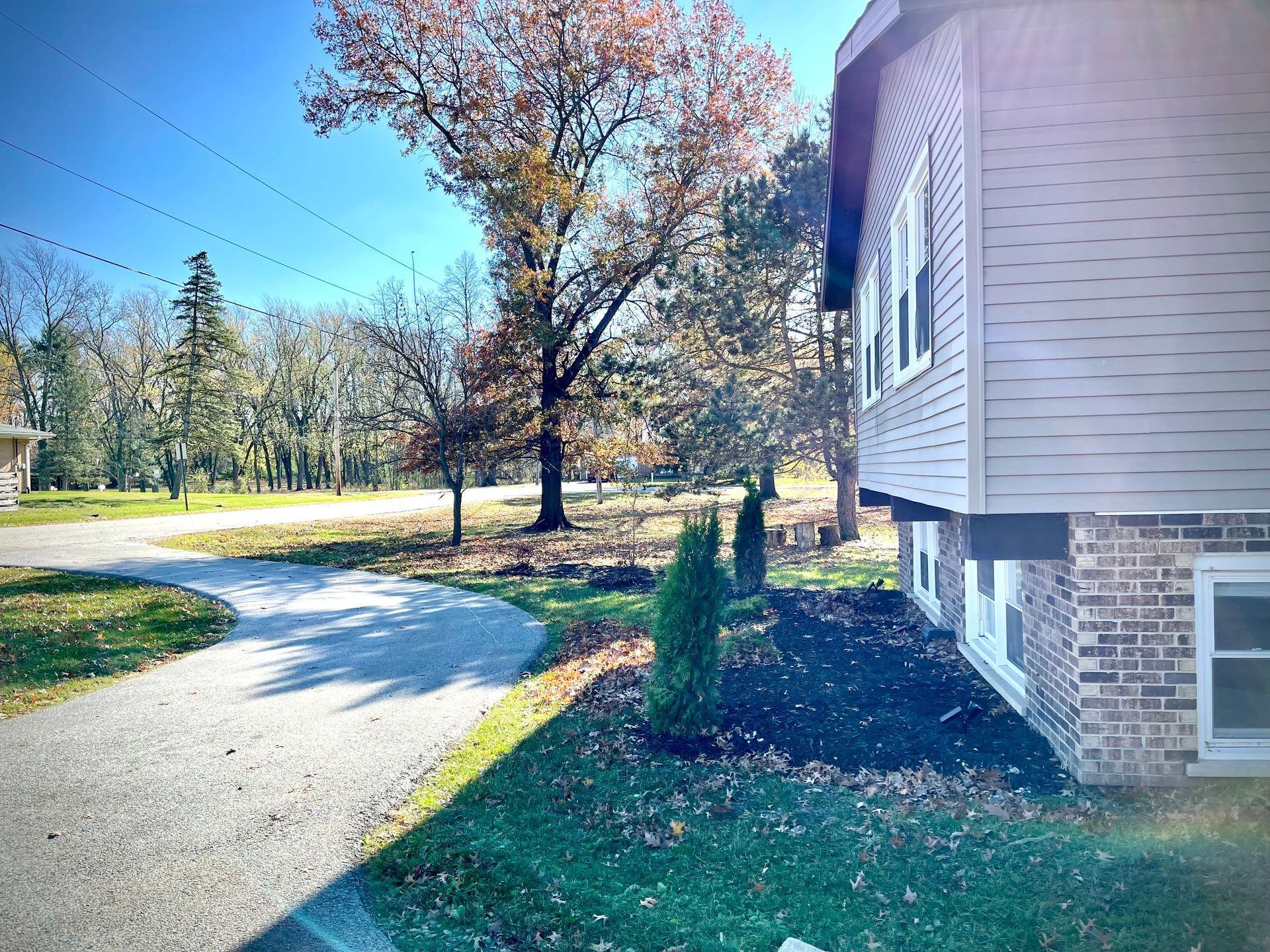 A house with a driveway leading to it and trees in the background.