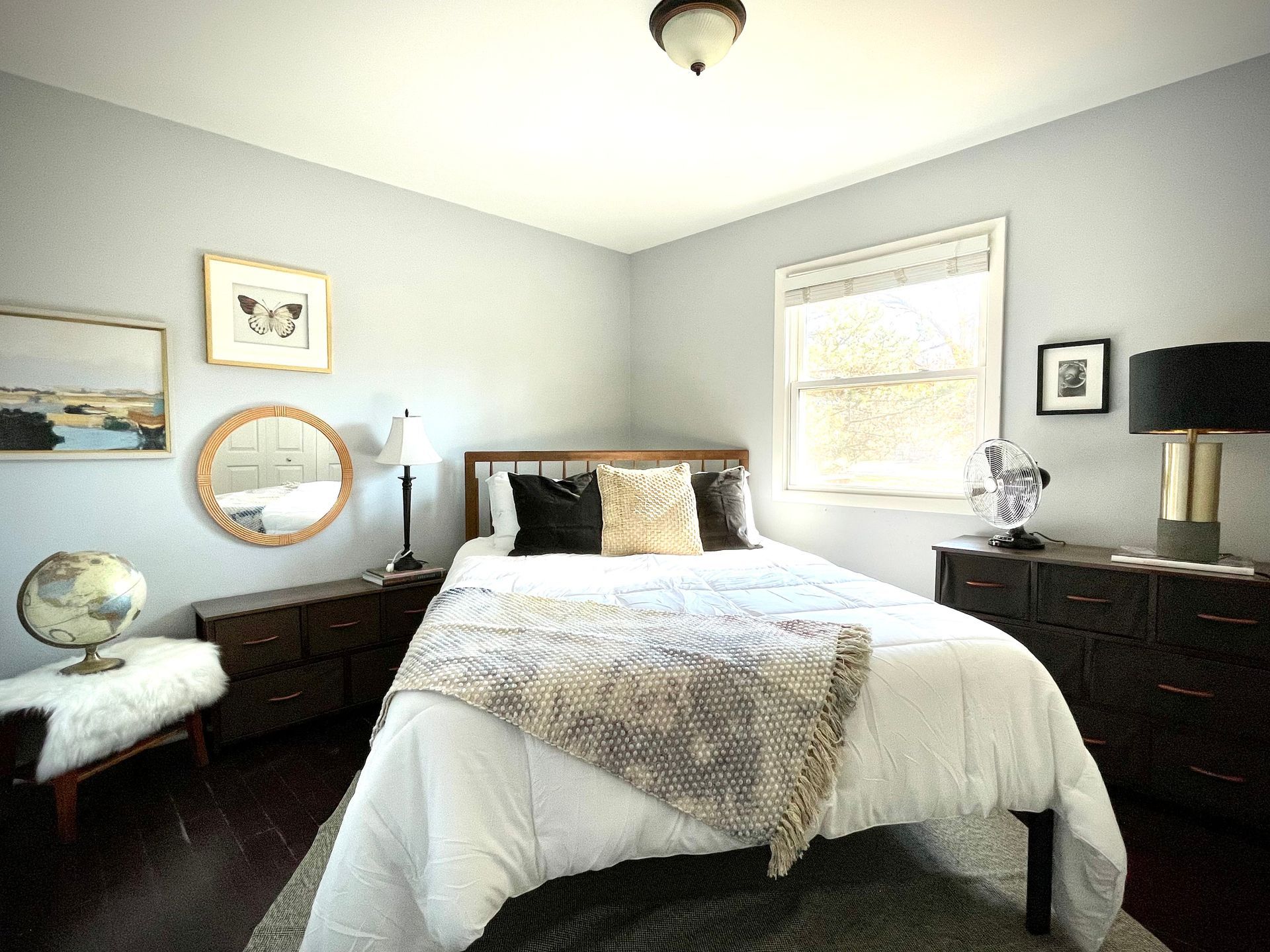 A bedroom with a bed , dresser , mirror and globe.
