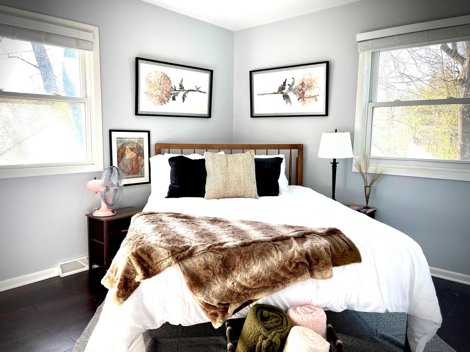 A bedroom with a bed , two windows and a lamp