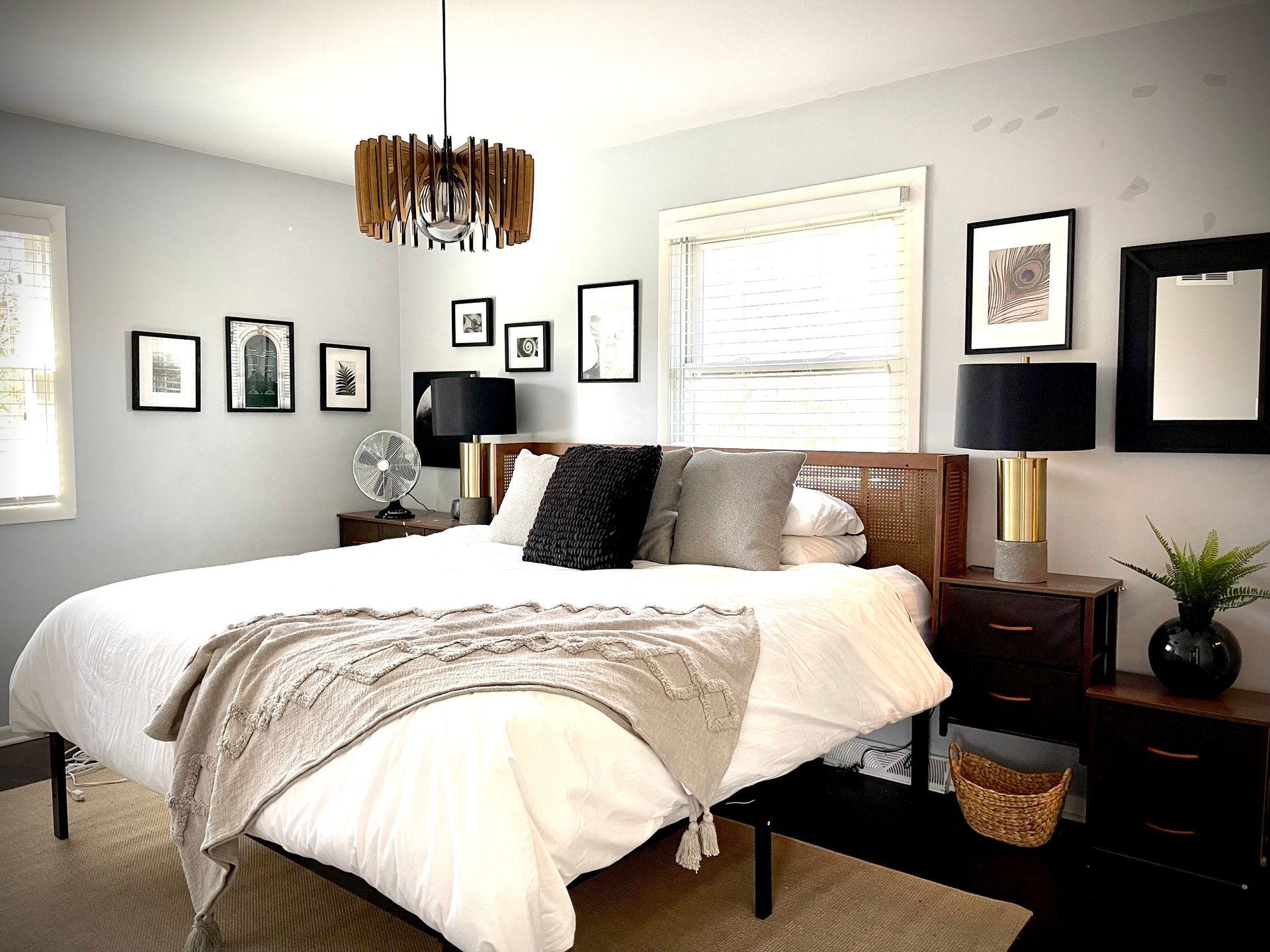 A bedroom with a bed , nightstands , lamps and pictures on the wall.
