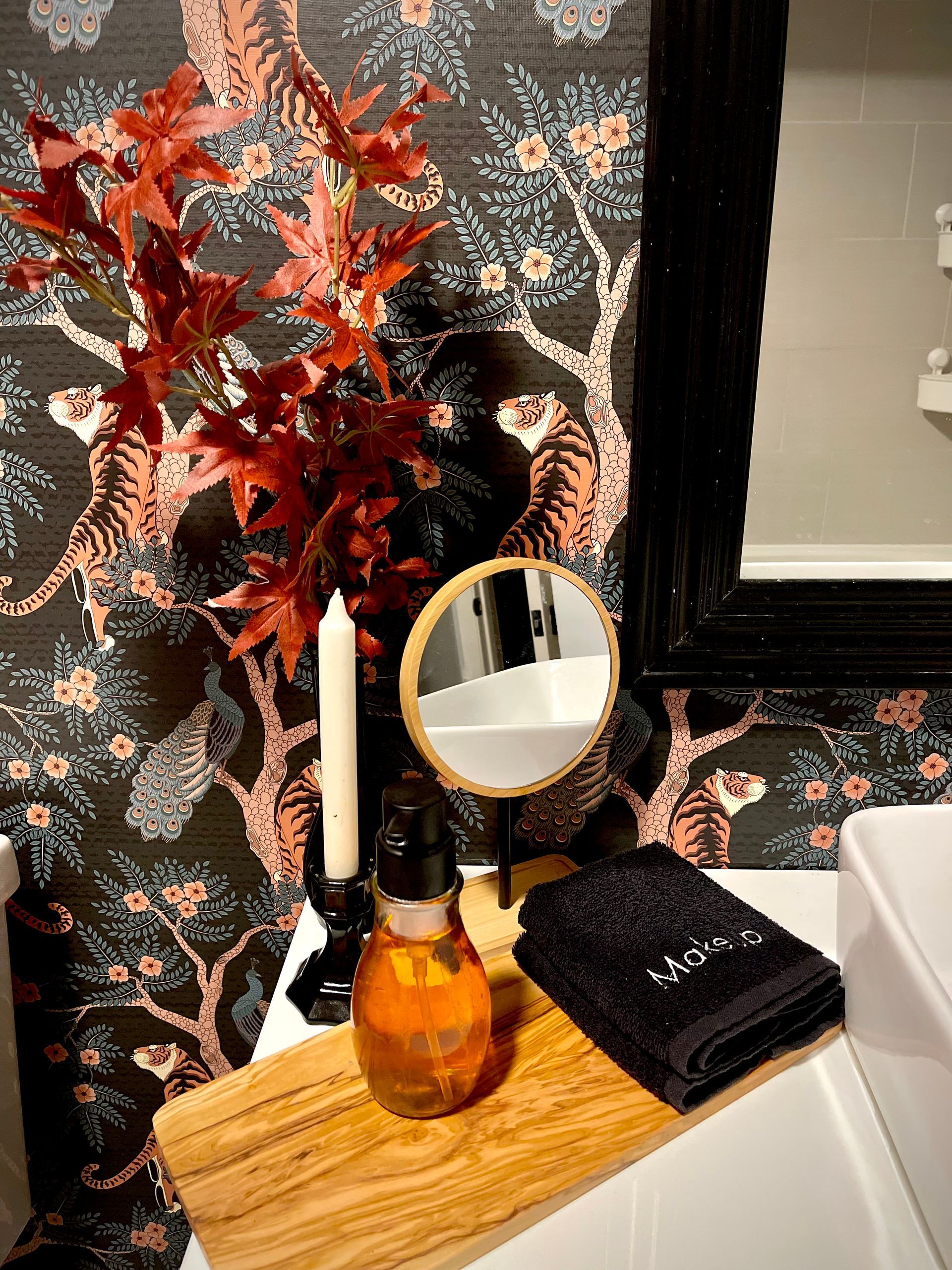 A bathroom with a sink , mirror , candles and a bathtub tray