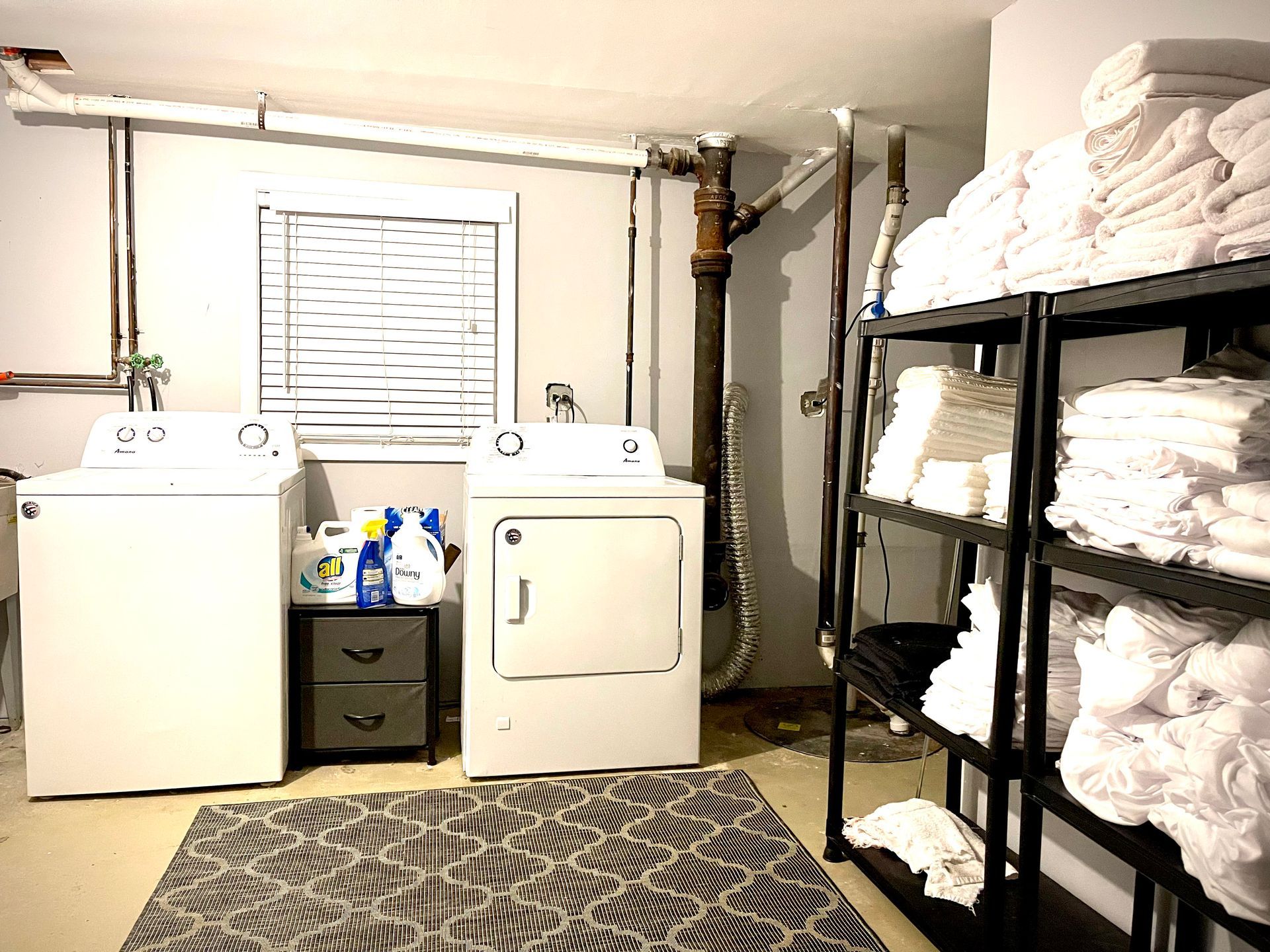 A laundry room with a washer and dryer and shelves filled with towels.