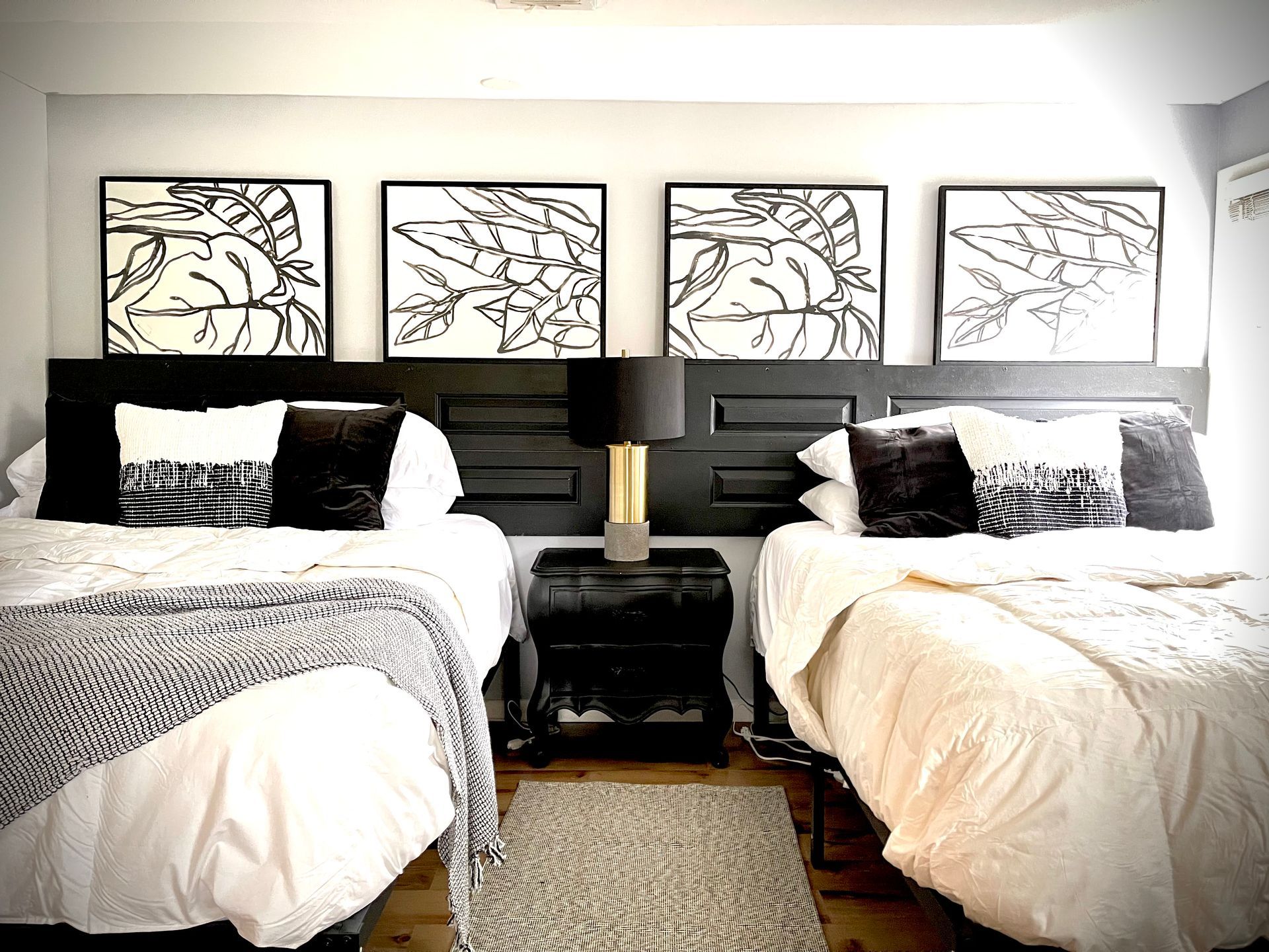 A bedroom with two beds and three paintings on the wall.