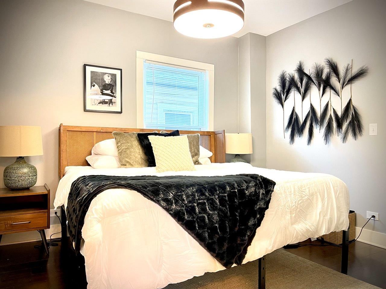 A bedroom with a bed , nightstand , lamp and a picture on the wall.