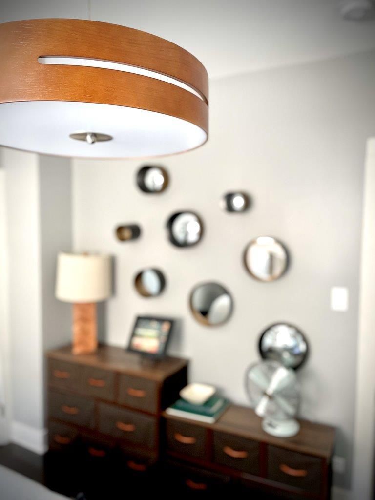 A room with a dresser and a lamp and mirrors on the wall