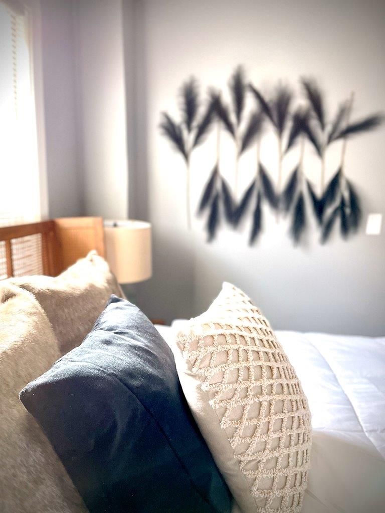 A bedroom with a bed and pillows and a painting on the wall