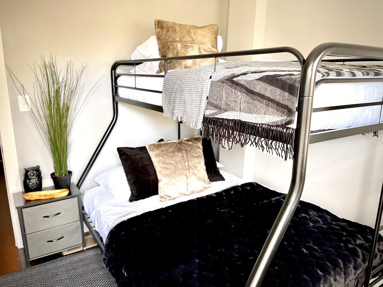 A bedroom with two bunk beds and a nightstand.