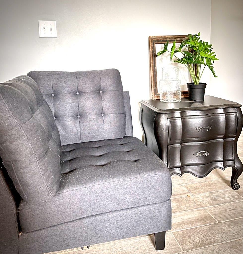 A gray chair and a black nightstand in a living room