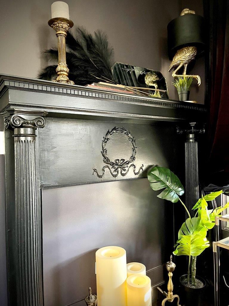 A mantle with candles and a plant on it in a living room.