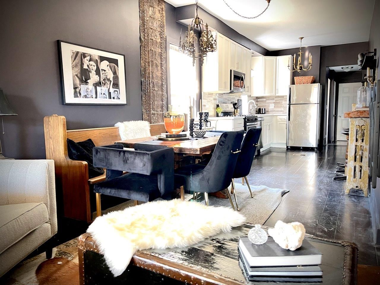 A living room with a dining table and chairs and a picture on the wall.
