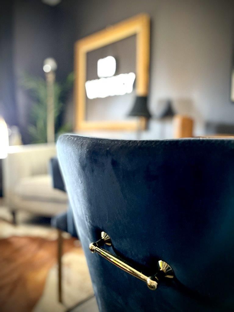 A blue chair with gold handles is in a living room.