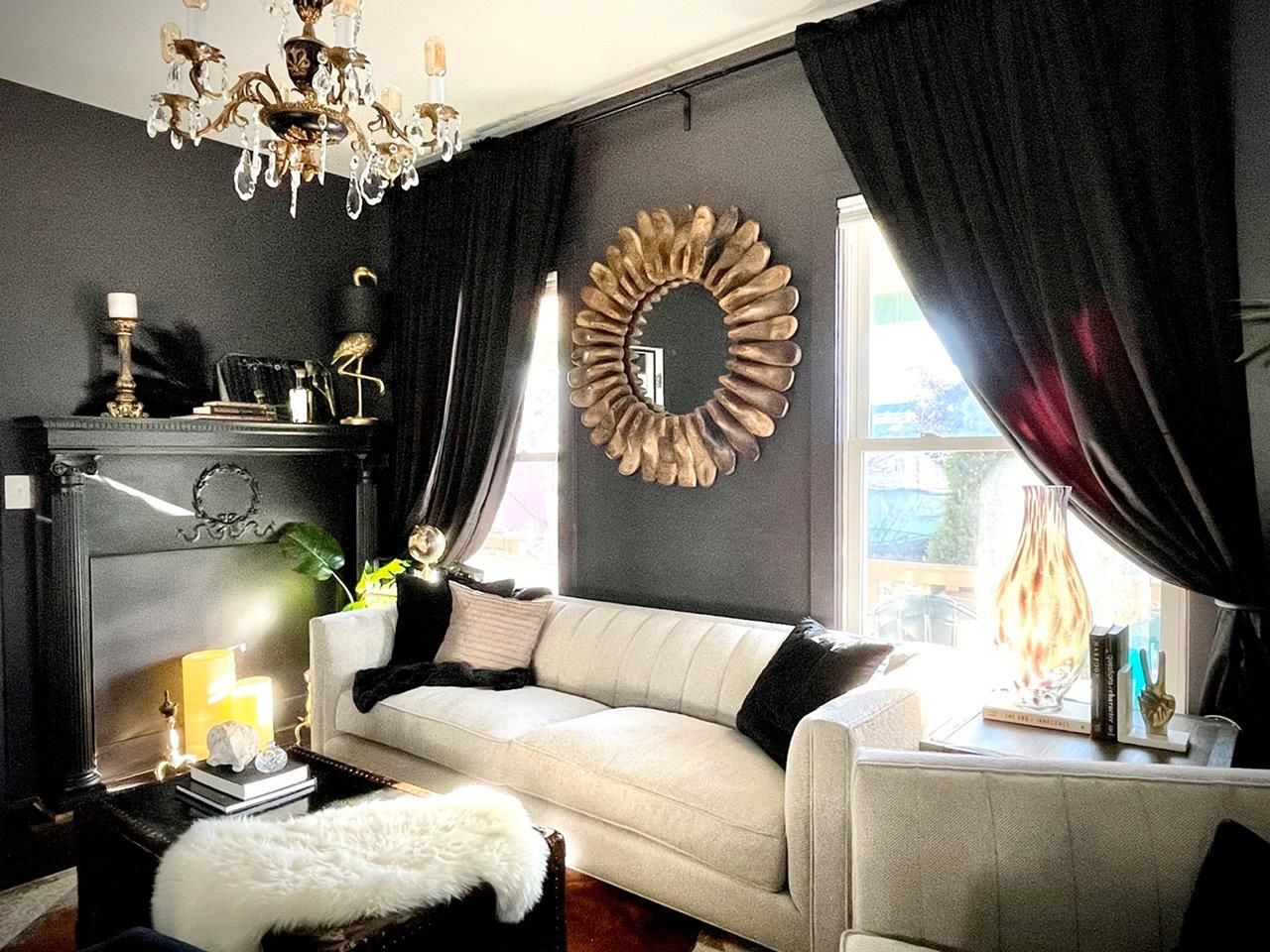 A living room with a couch , fireplace , mirror and chandelier.