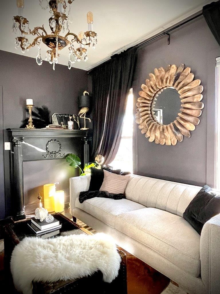 A living room with a couch , fireplace , mirror and chandelier.