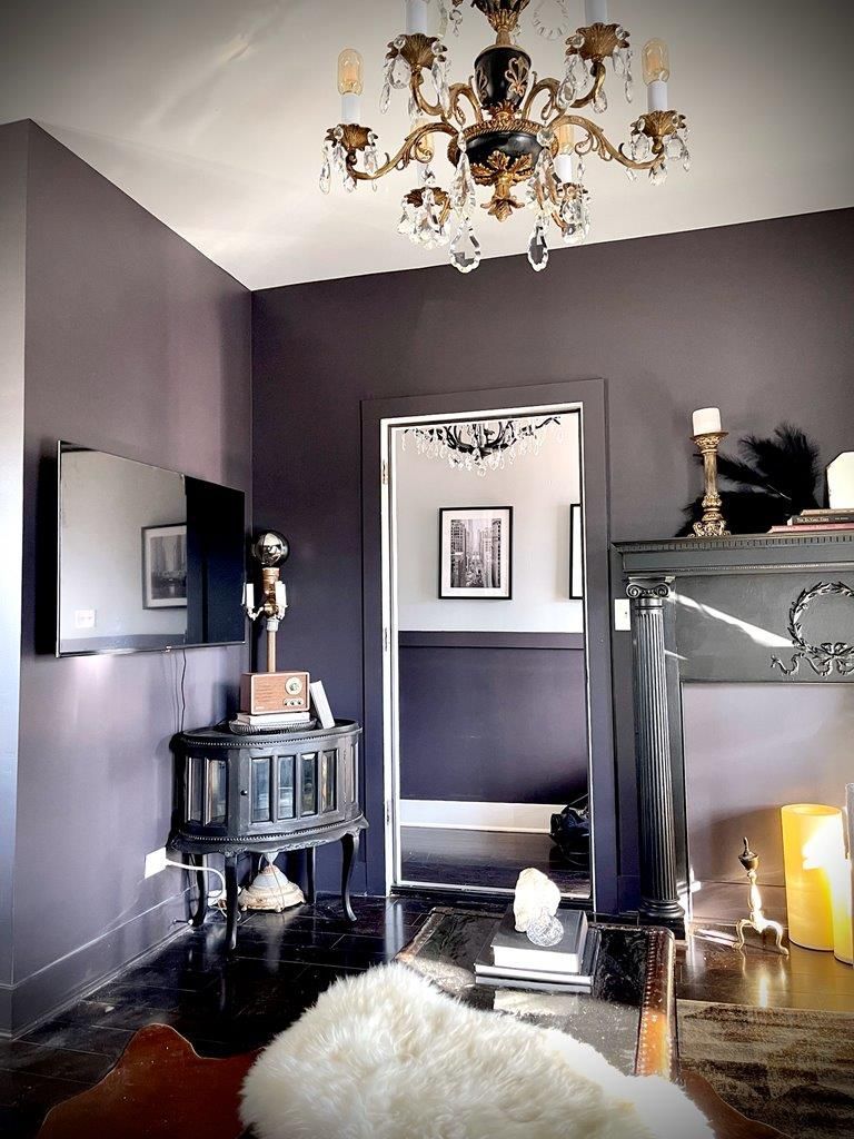 A living room with purple walls and a chandelier hanging from the ceiling.
