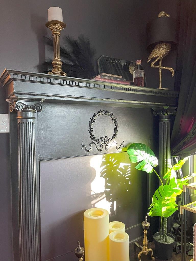 A mantle with candles and a lamp on top of it.