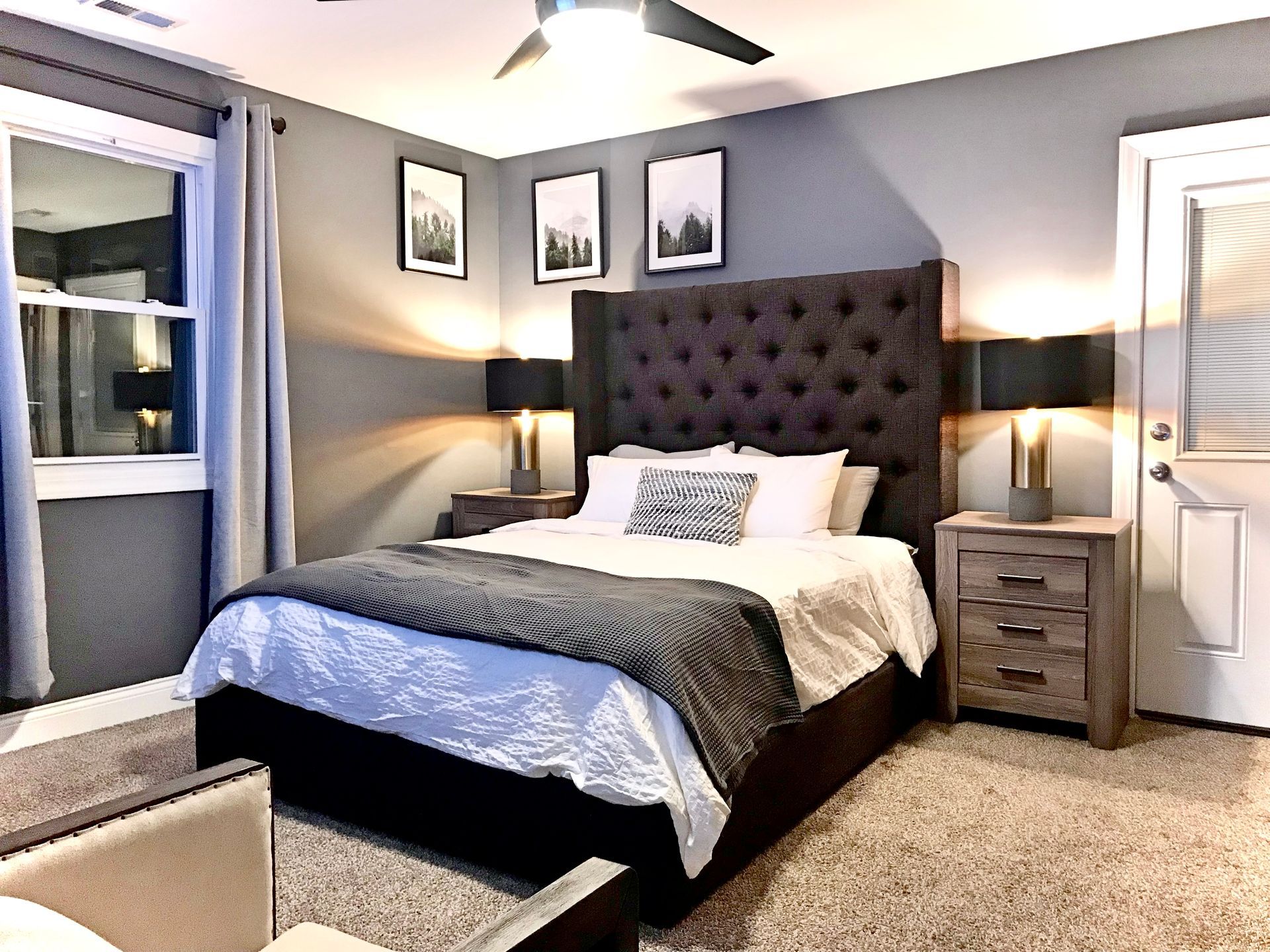A bedroom with a king size bed , nightstands , lamps and a ceiling fan.