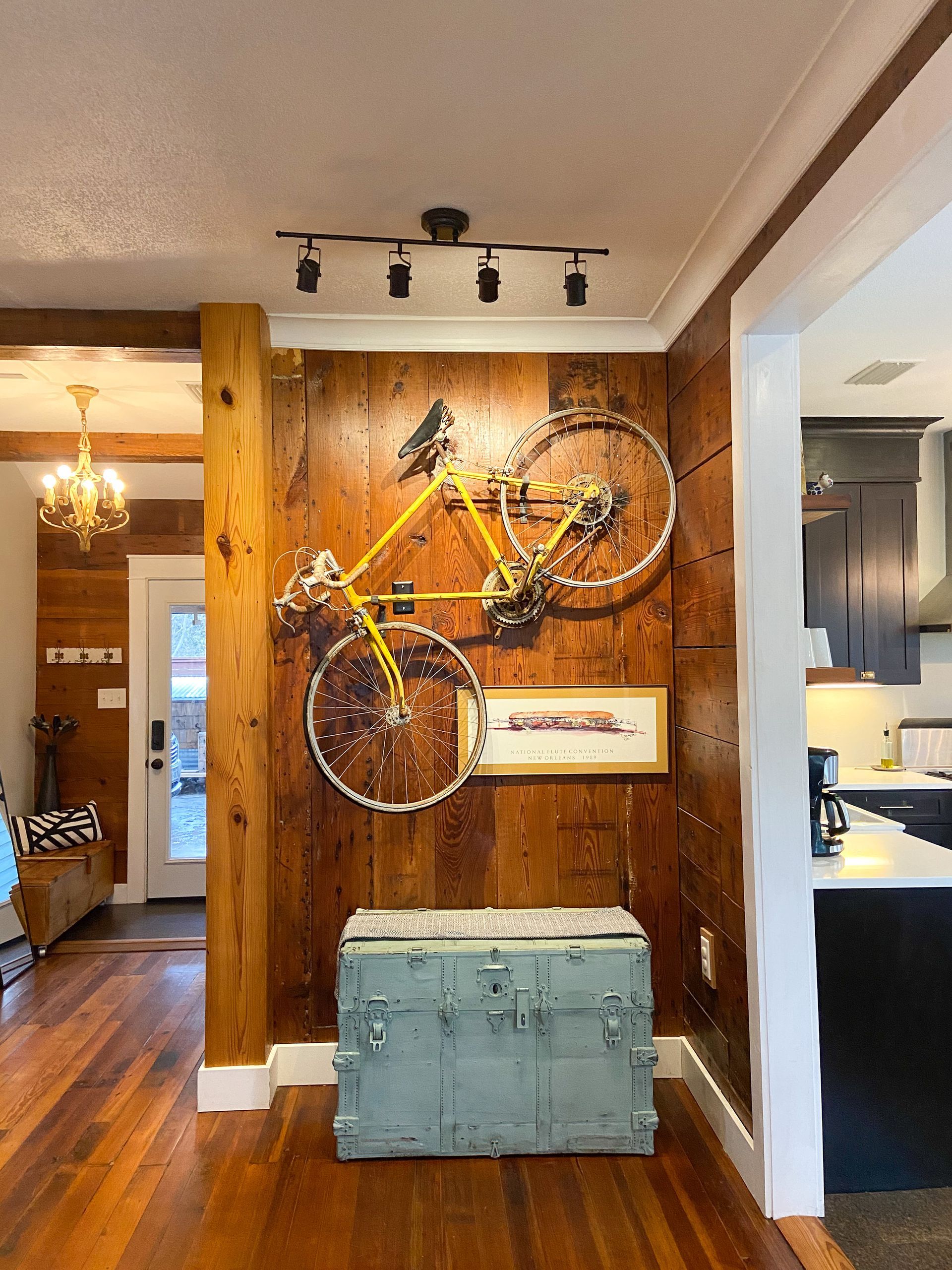 A bicycle is hanging on a wooden wall next to a blue trunk