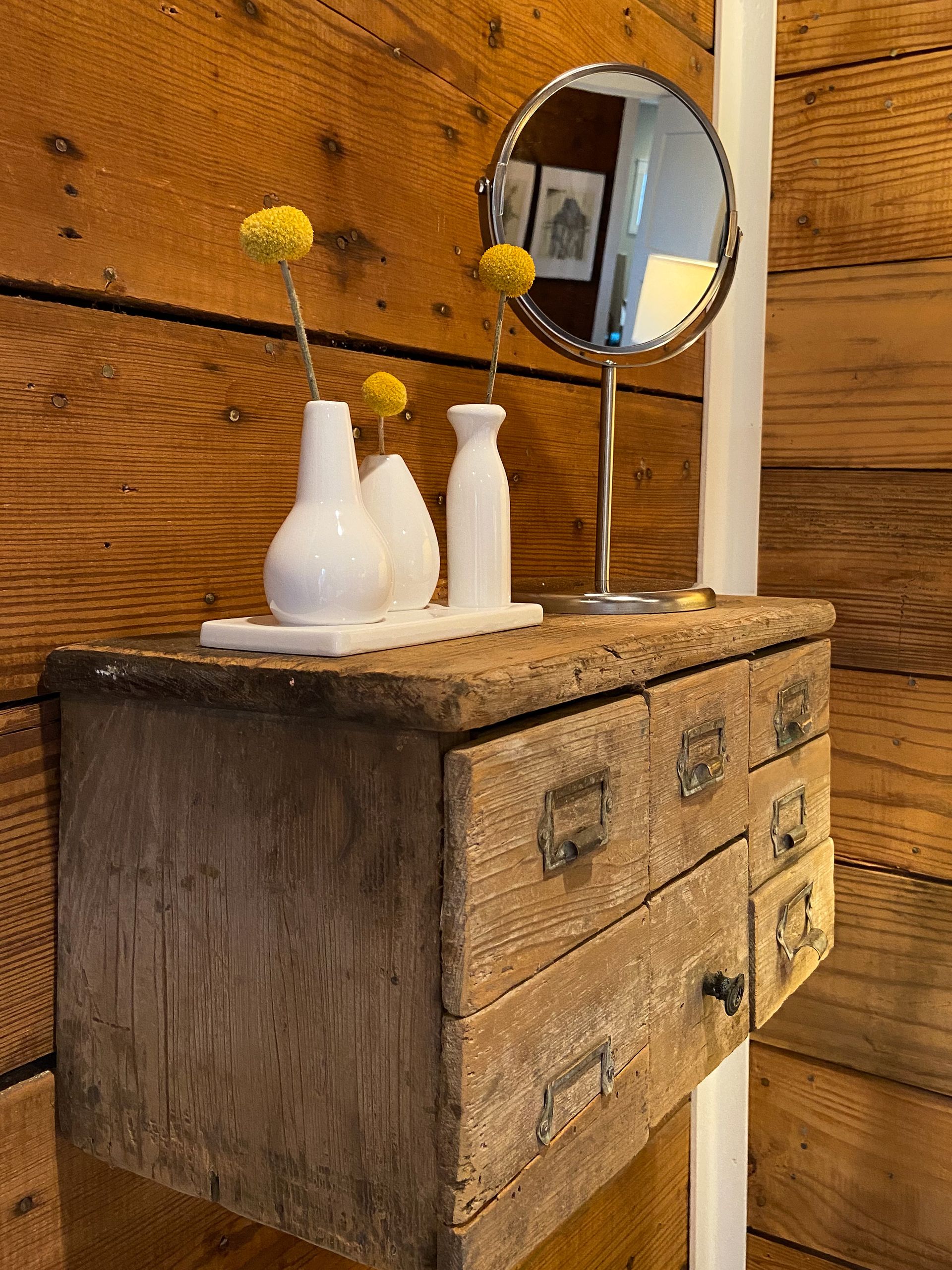 A wooden dresser with a mirror and vases on it.
