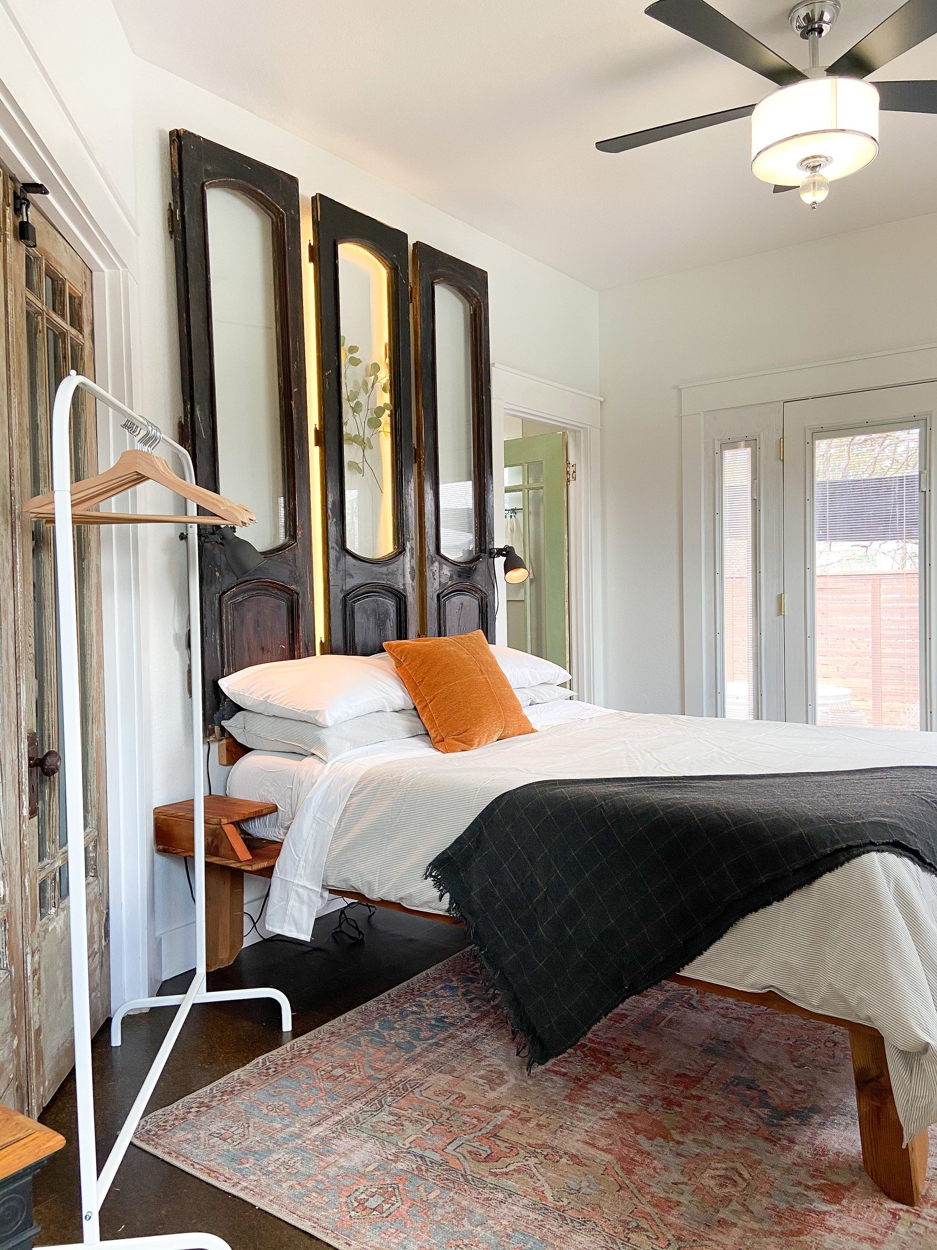 A bedroom with a bed , ceiling fan , mirrors and a rug.