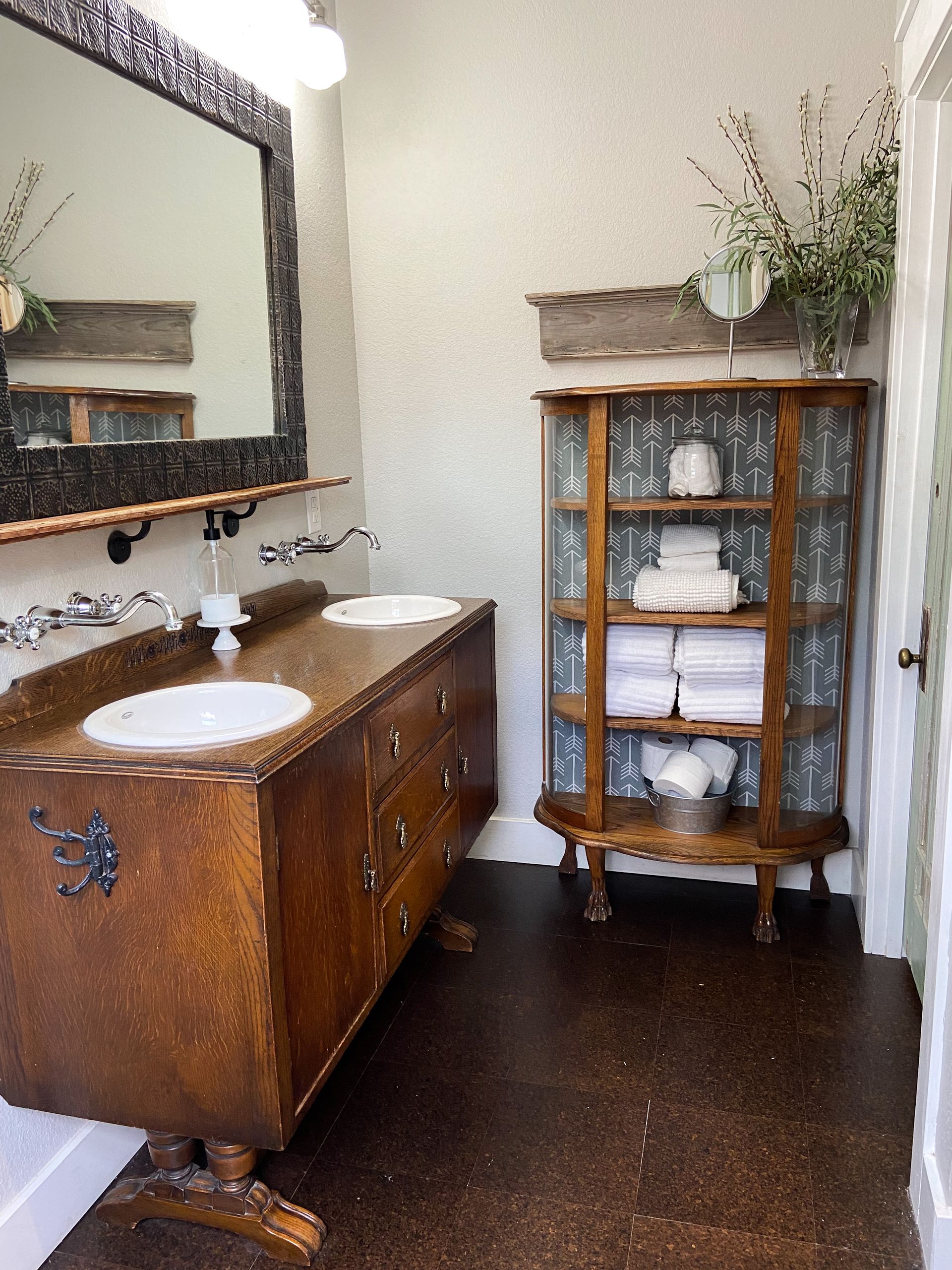 A bathroom with two sinks and a cabinet with towels on it