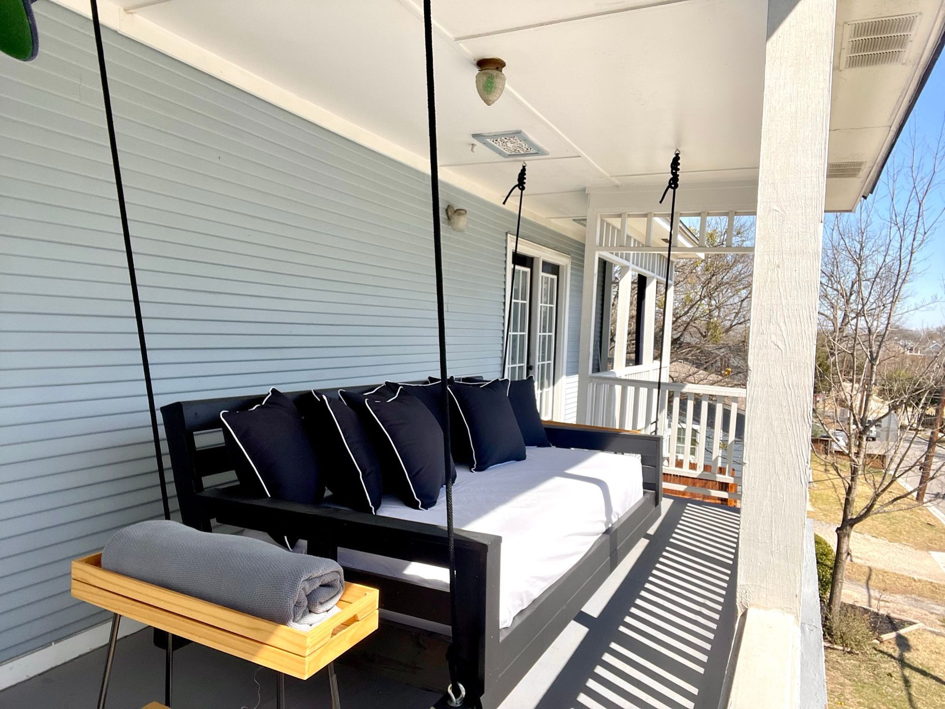 A porch with a couch hanging from the ceiling and a swing.