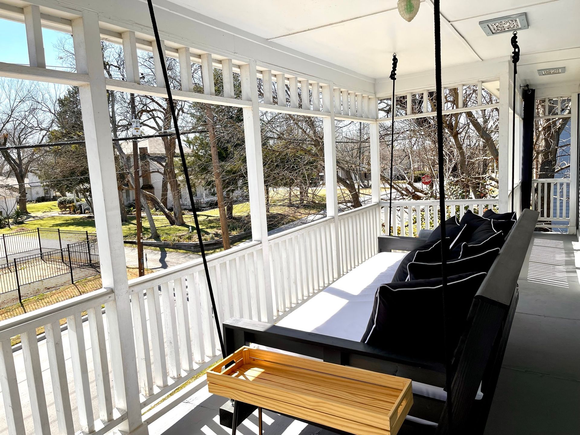 A porch with a swing and a tray on it.