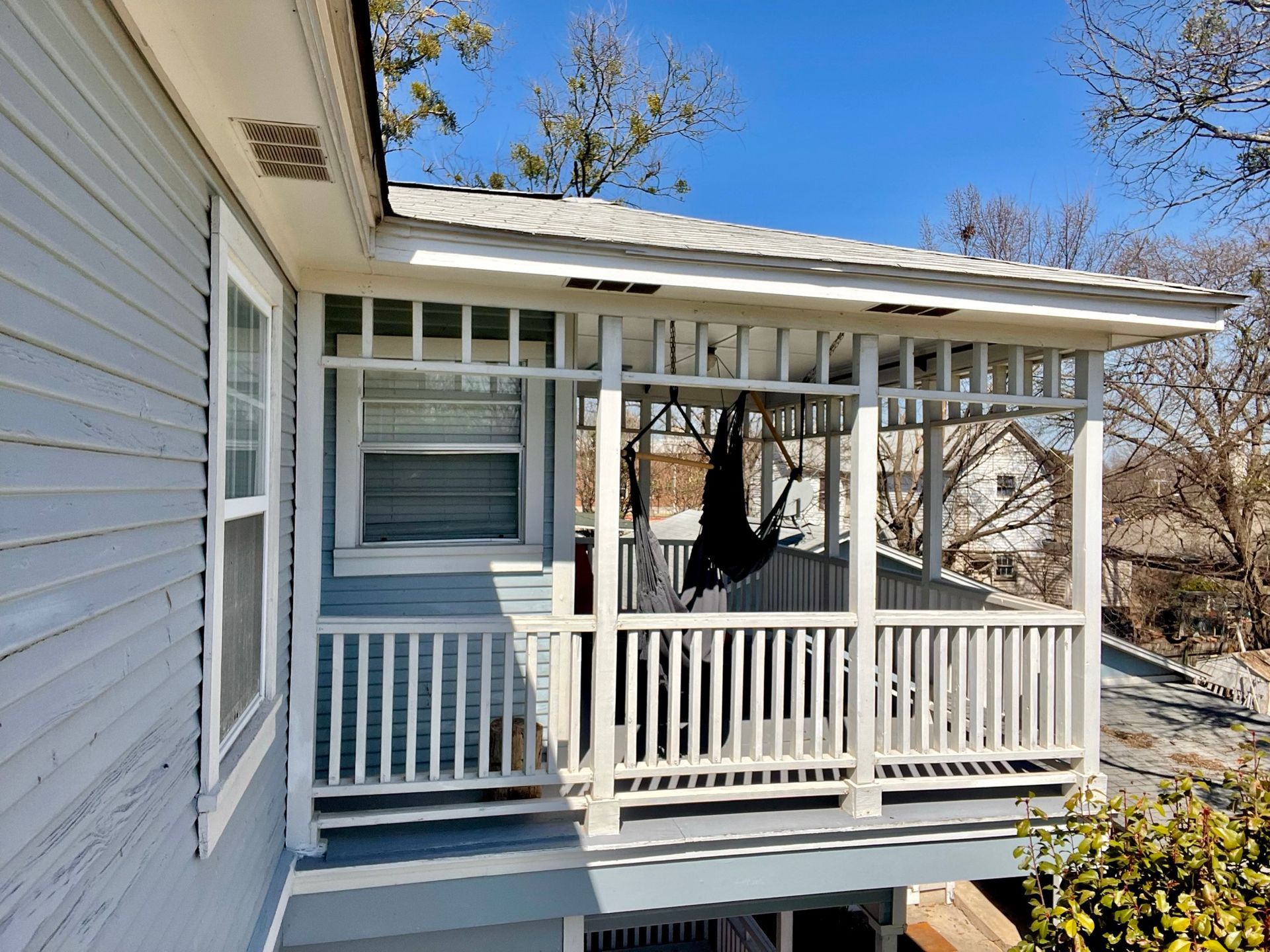 A porch with a white railing on the side of a house.