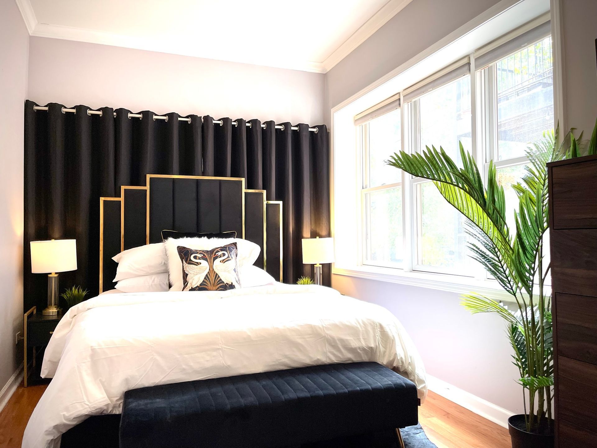 A bedroom with a bed , dresser , lamps and a window.