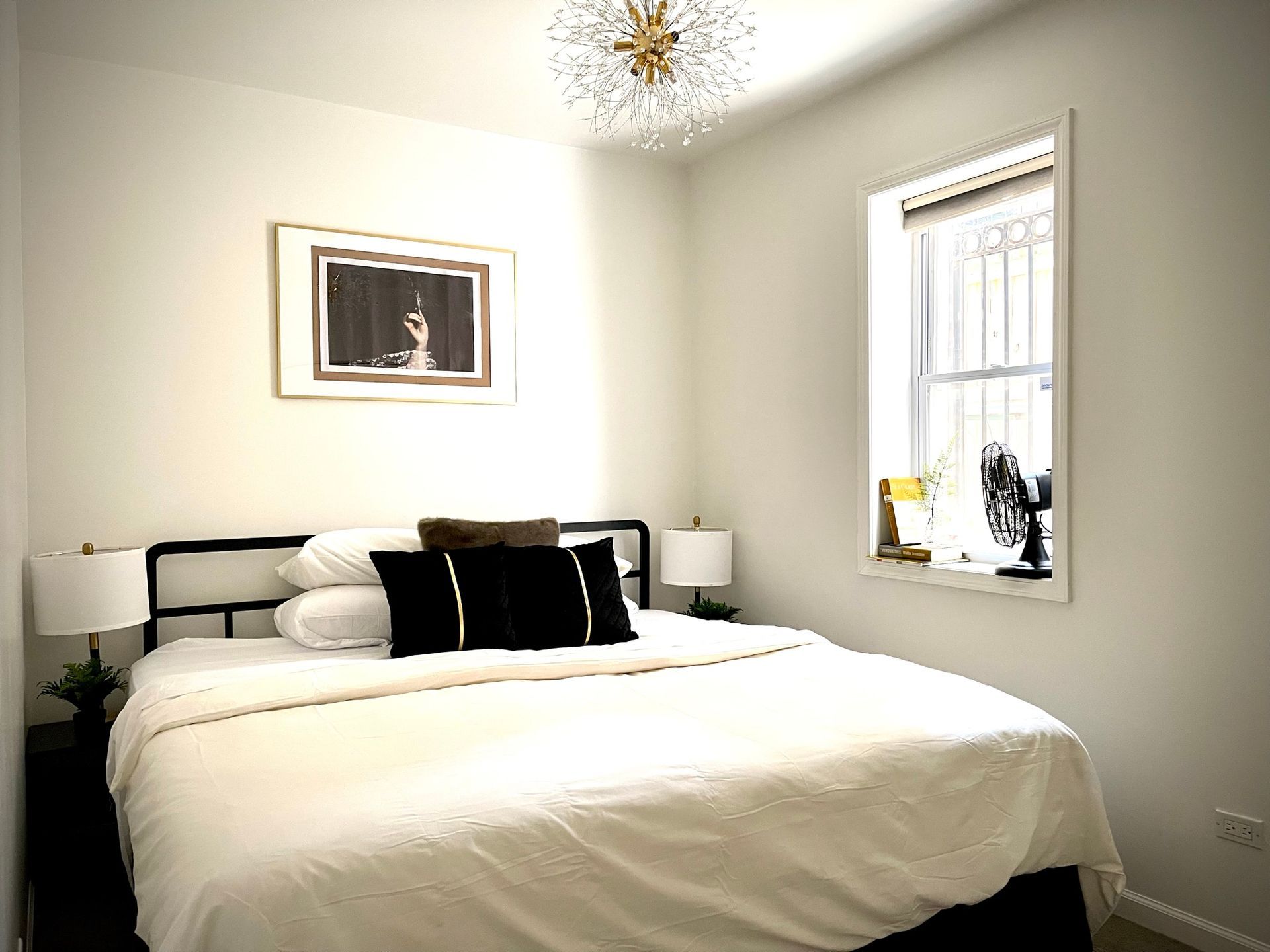 A bedroom with a bed , two lamps and a window.