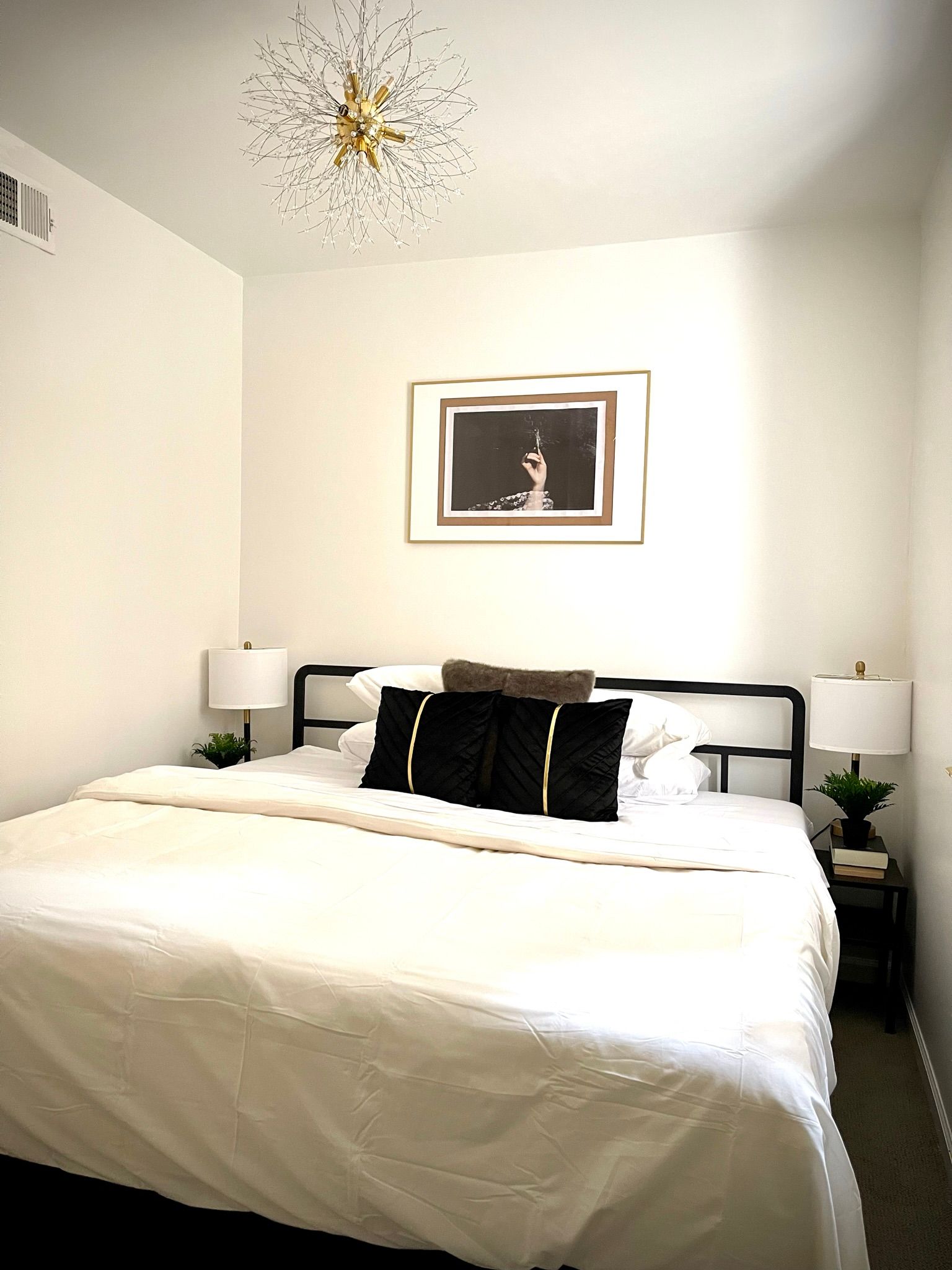 A bedroom with a large bed and a picture on the wall above it