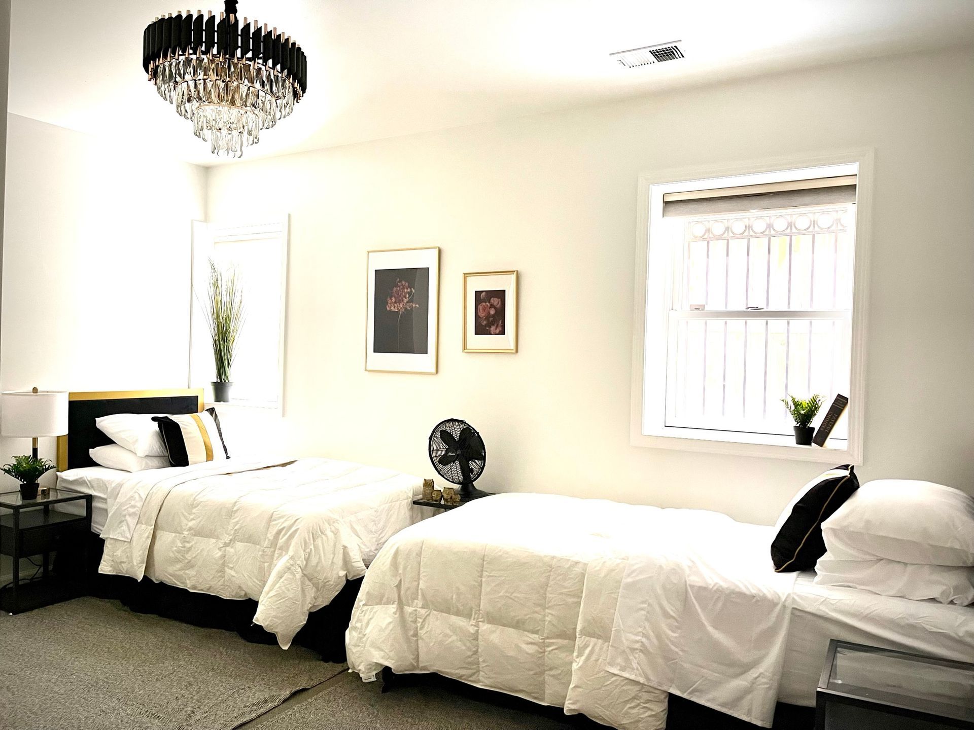 A bedroom with two beds and a chandelier hanging from the ceiling.