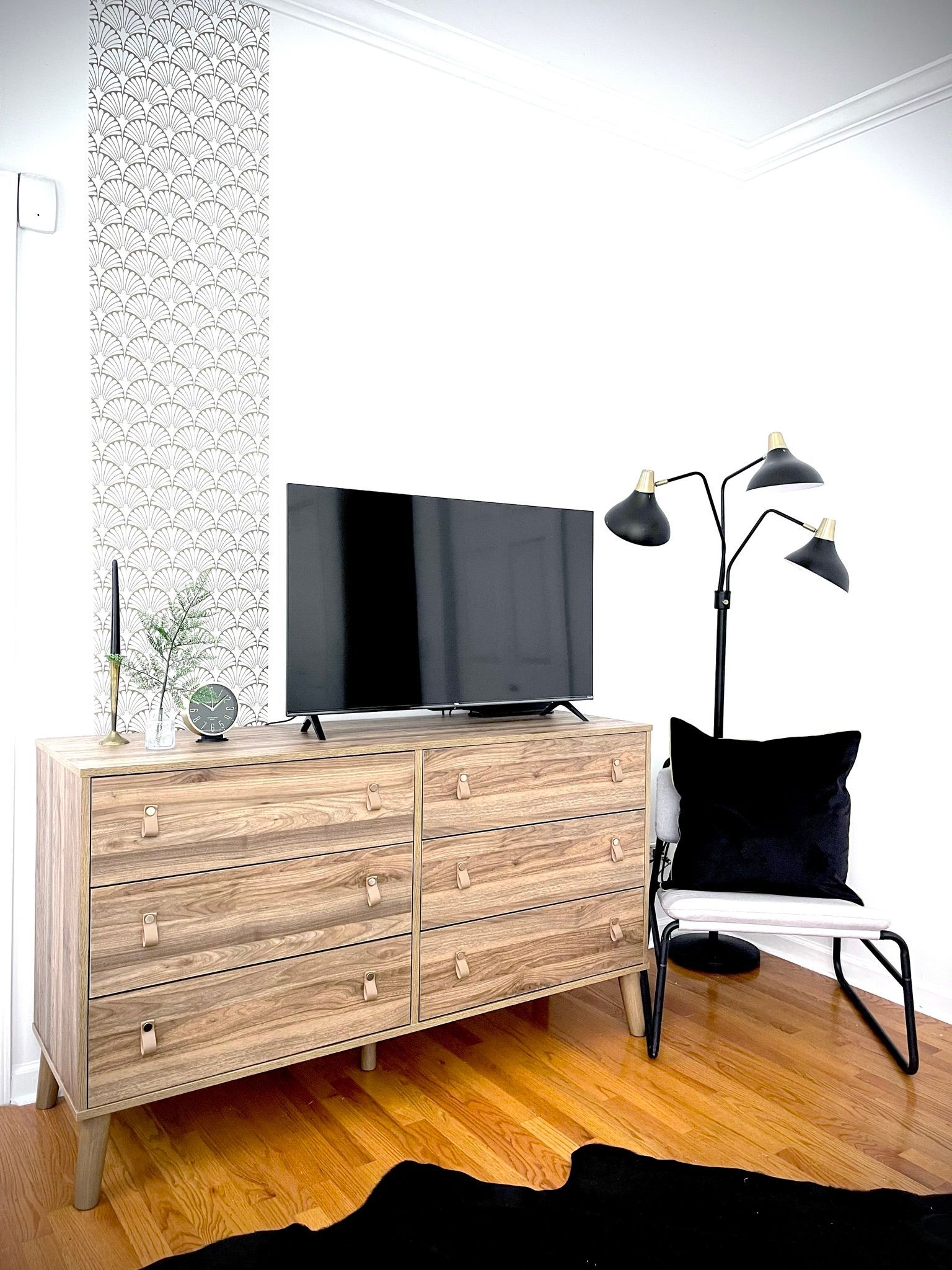 A living room with a dresser , chair , lamp and television.