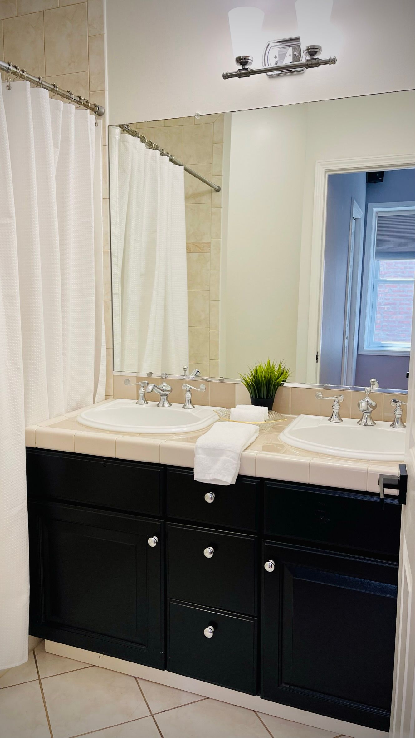 A bathroom with two sinks , a mirror and a shower curtain.