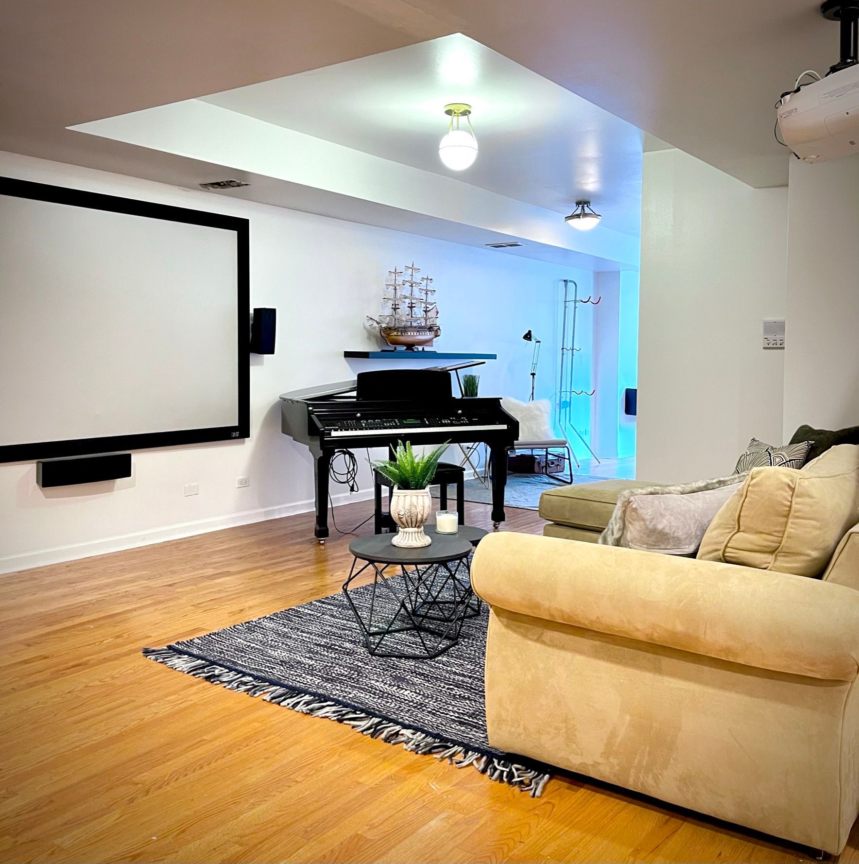 A living room with a piano and a projector screen