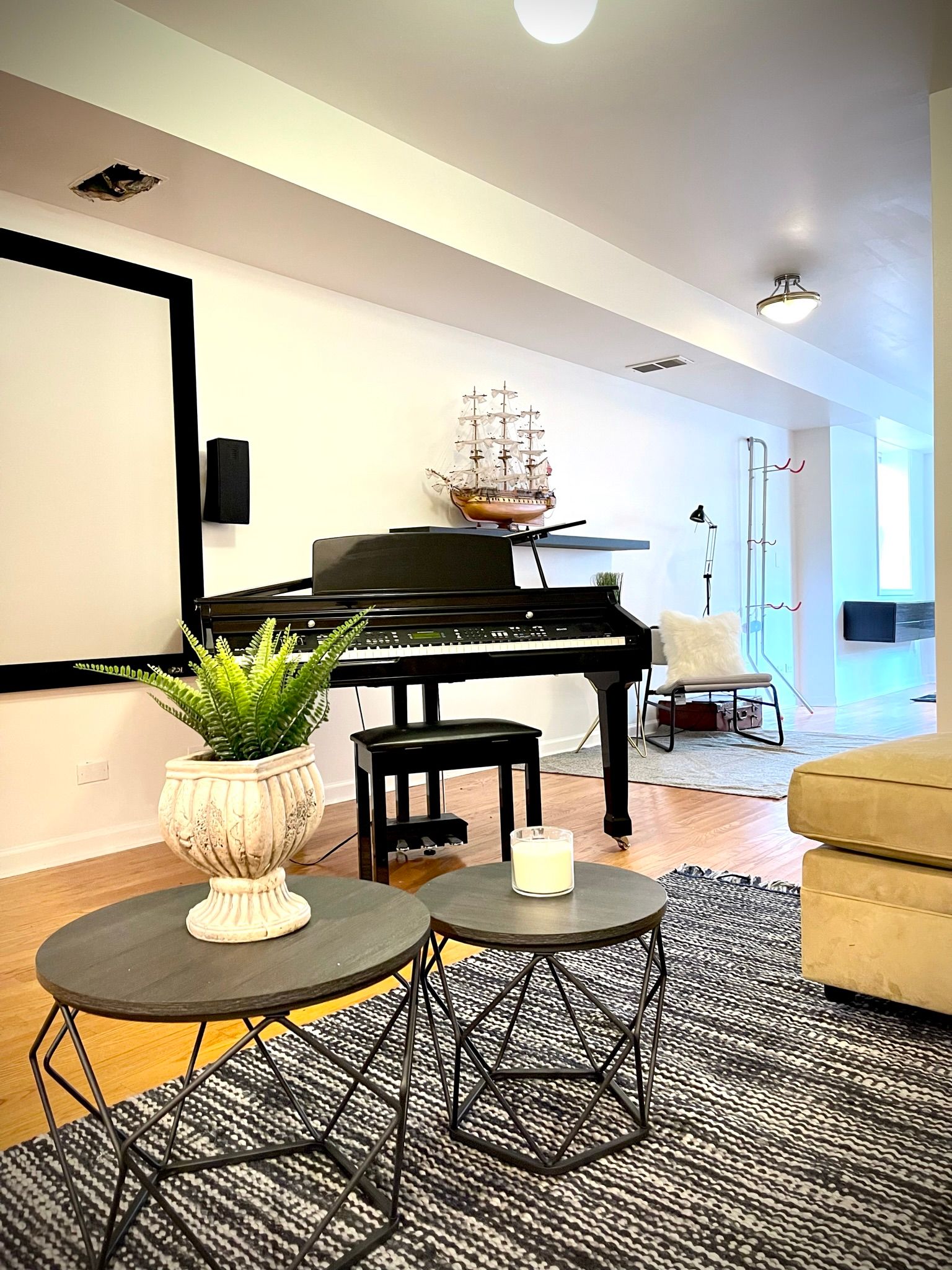 A living room with a piano and a projector screen.