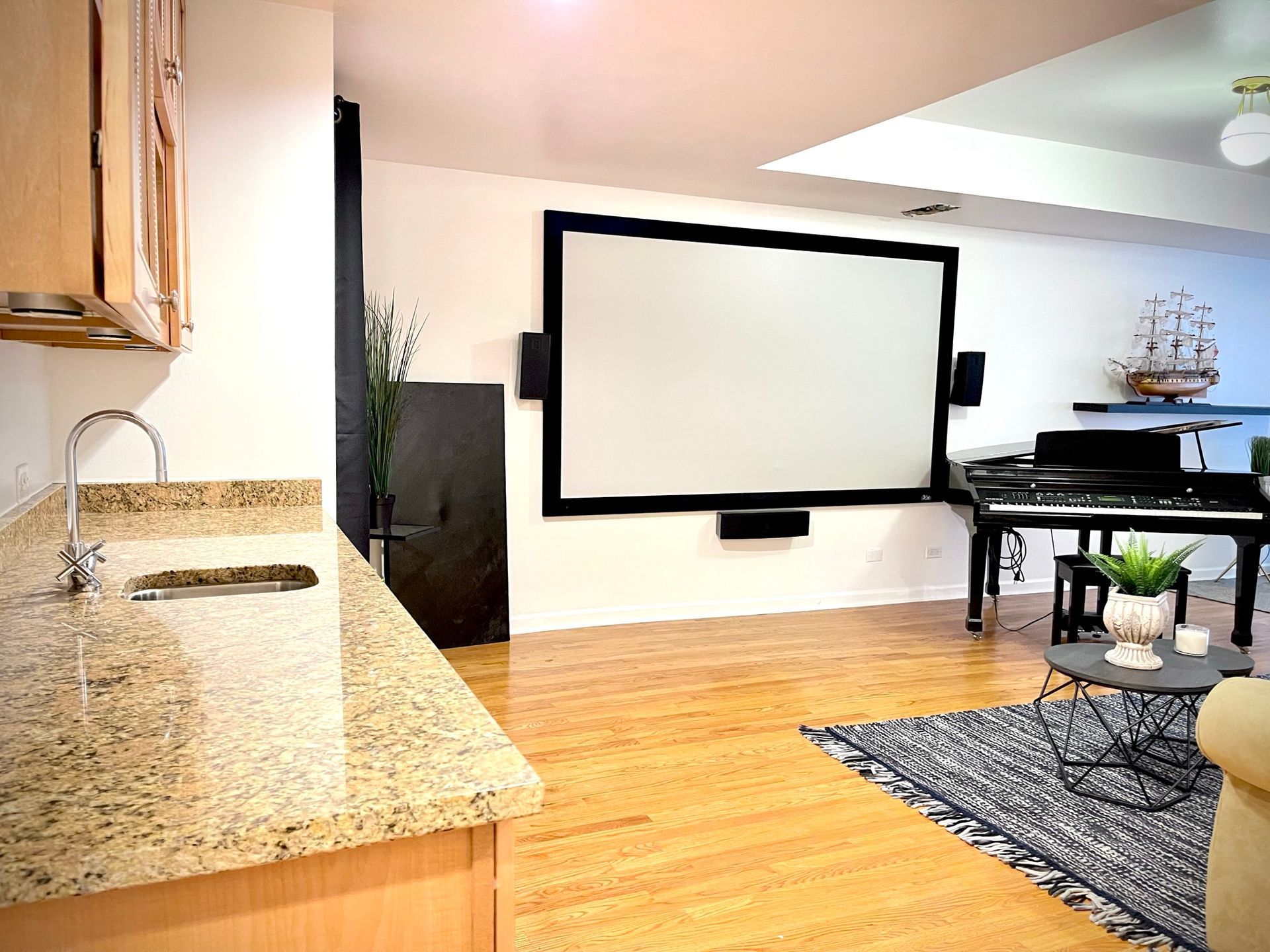 A living room with a projector screen and a piano.