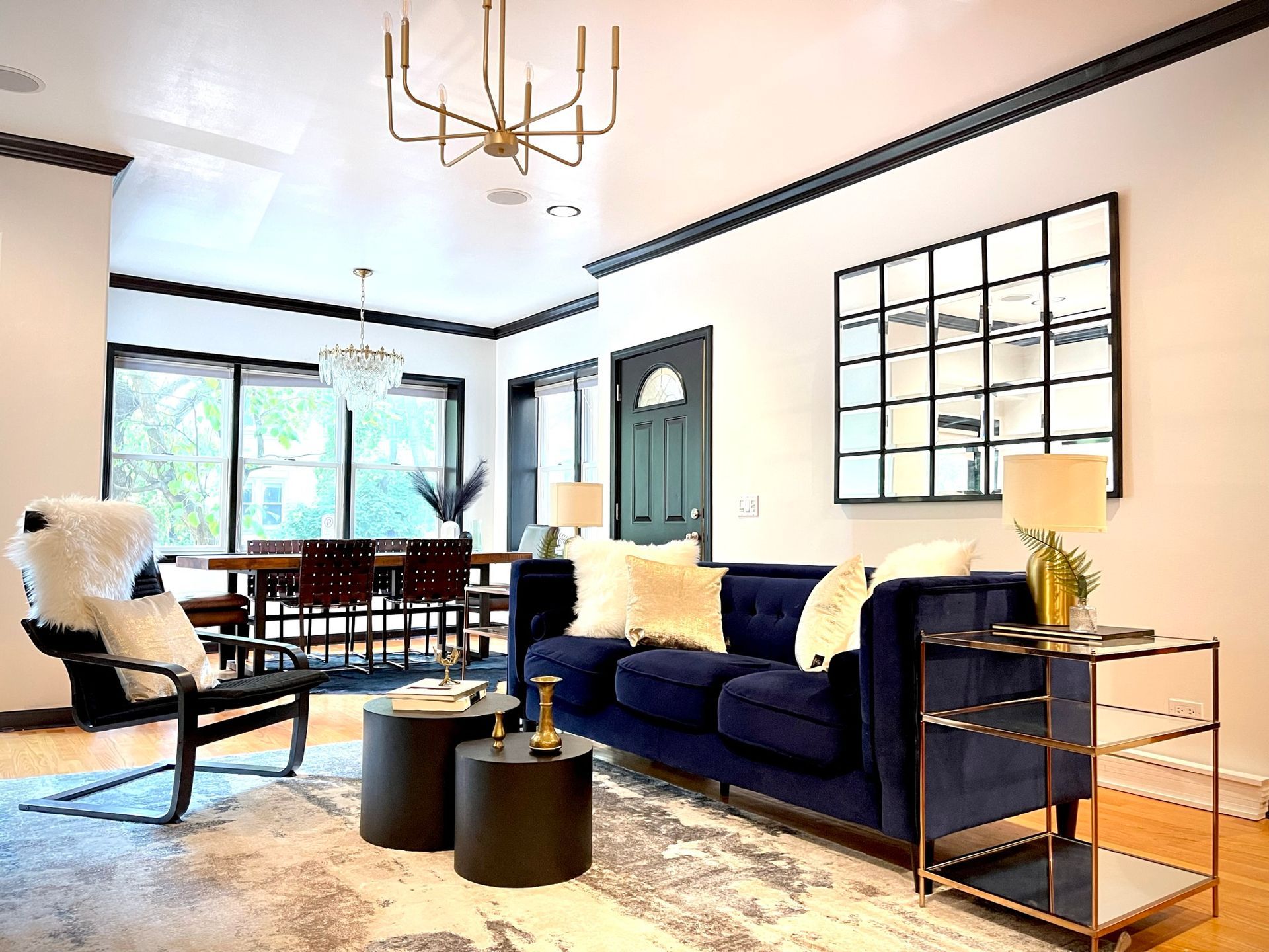 A living room with a blue couch , chairs , tables and a mirror.