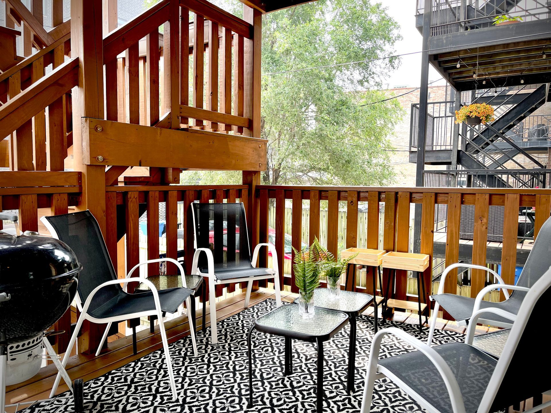 A balcony with chairs , a table and a grill.