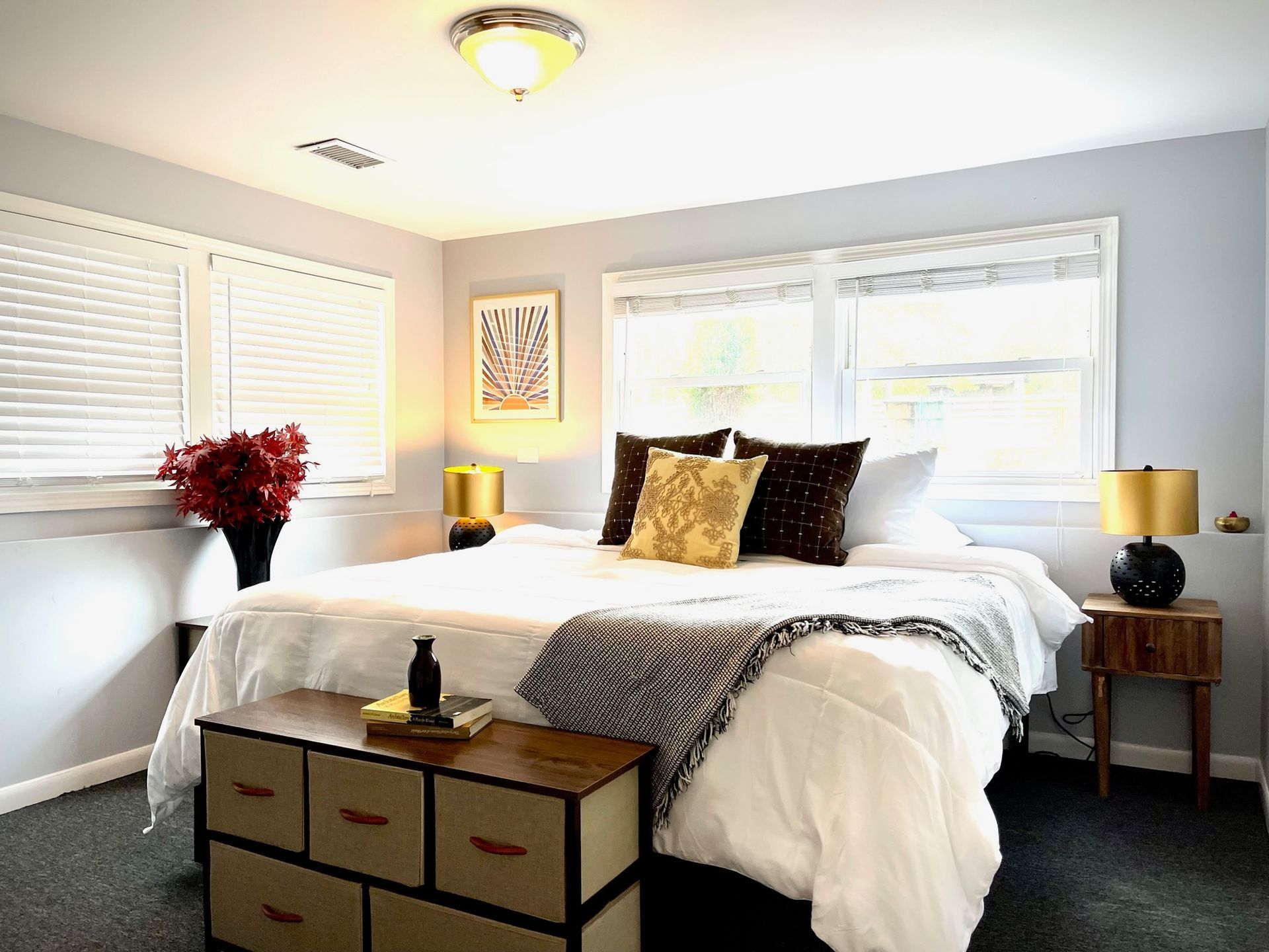 A bedroom with a king size bed , dresser , nightstand , and lamps.