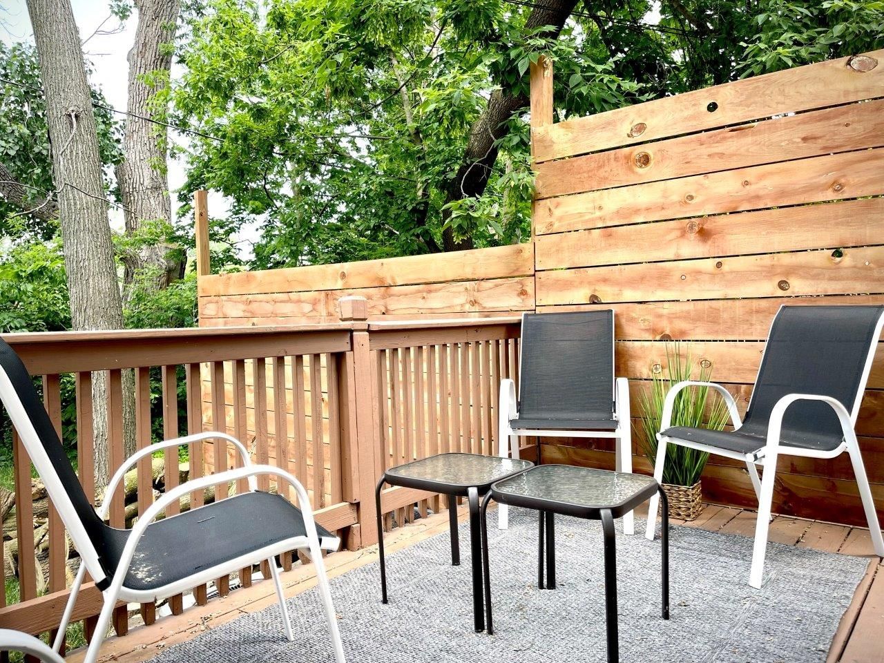 There are two chairs and a table on the deck.