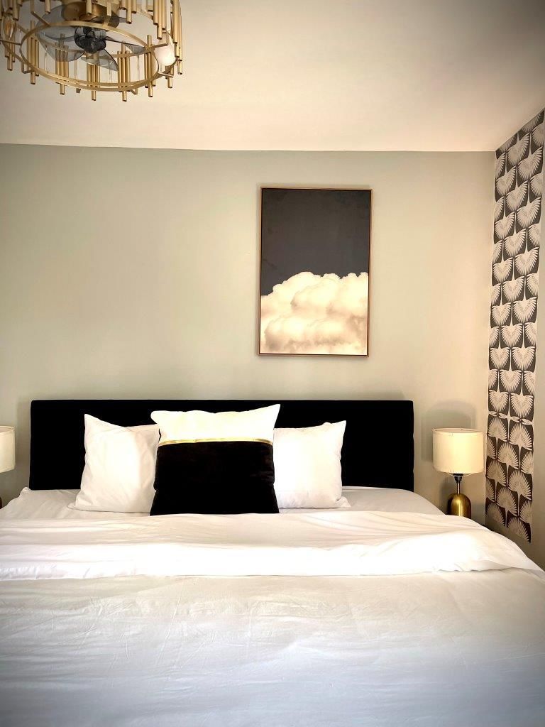 A bedroom with a large bed and a painting on the wall above it