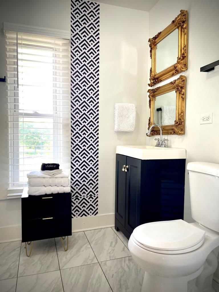 A bathroom with a toilet , sink and two mirrors