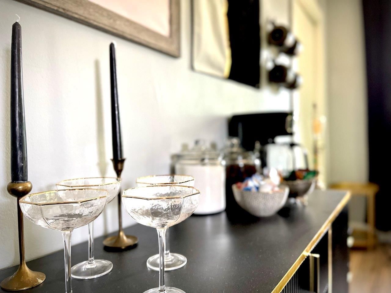 Two champagne glasses and two candles are on a table.