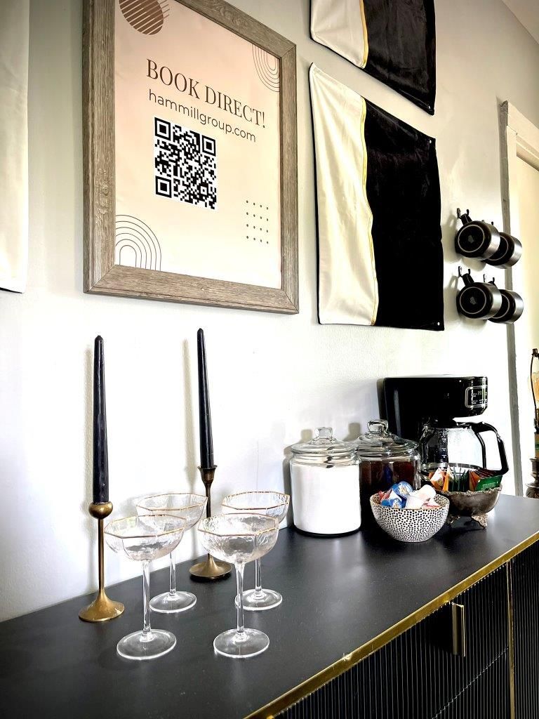 A table with glasses , candles , jars and a sign on the wall.