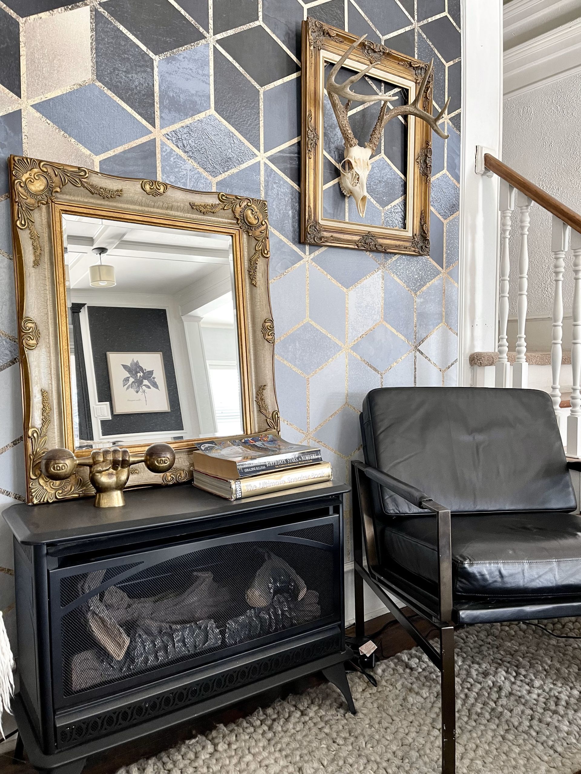 A living room with a fireplace , chair , mirror and stairs.