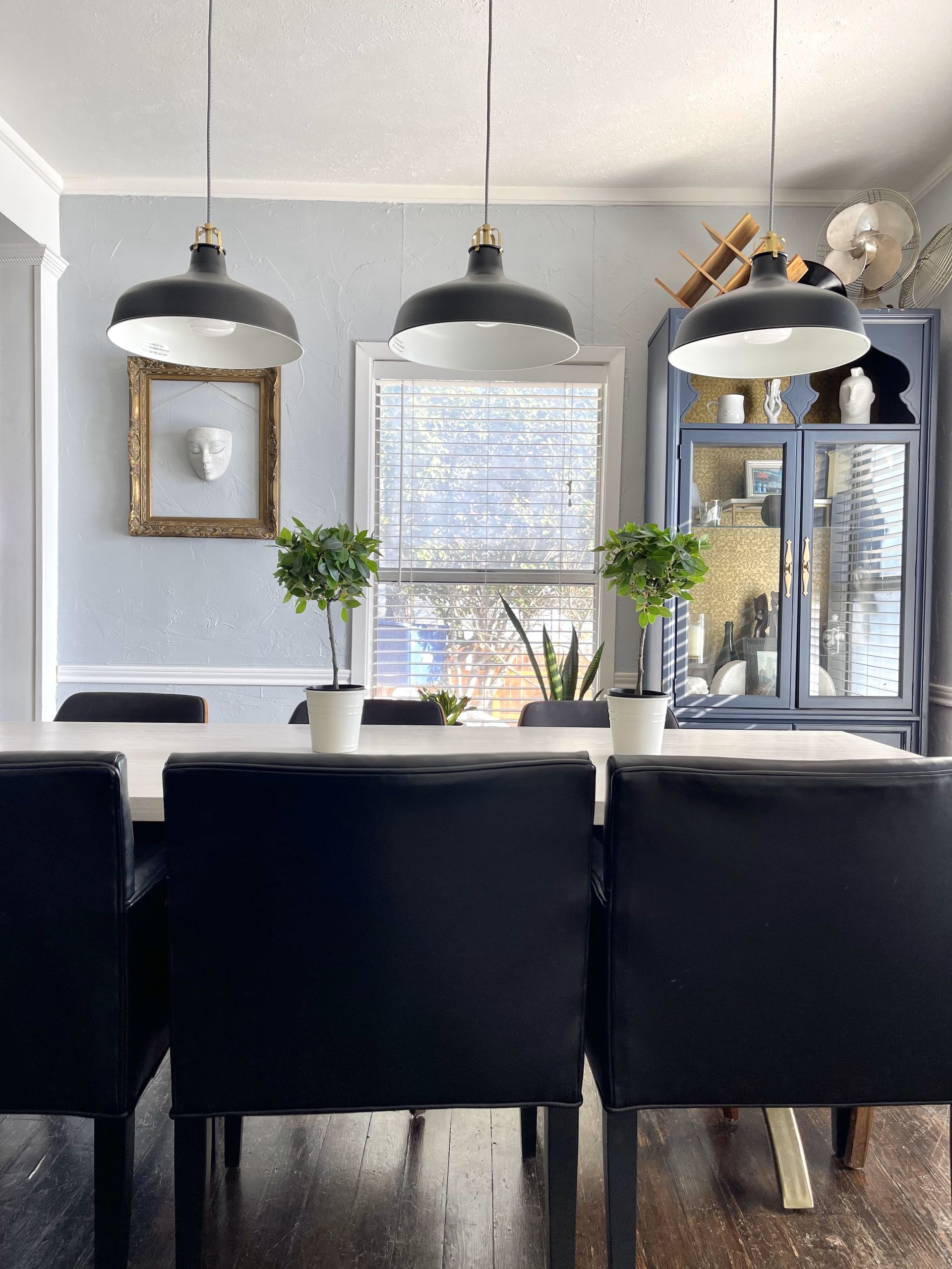 A dining room with a table and chairs and potted plants